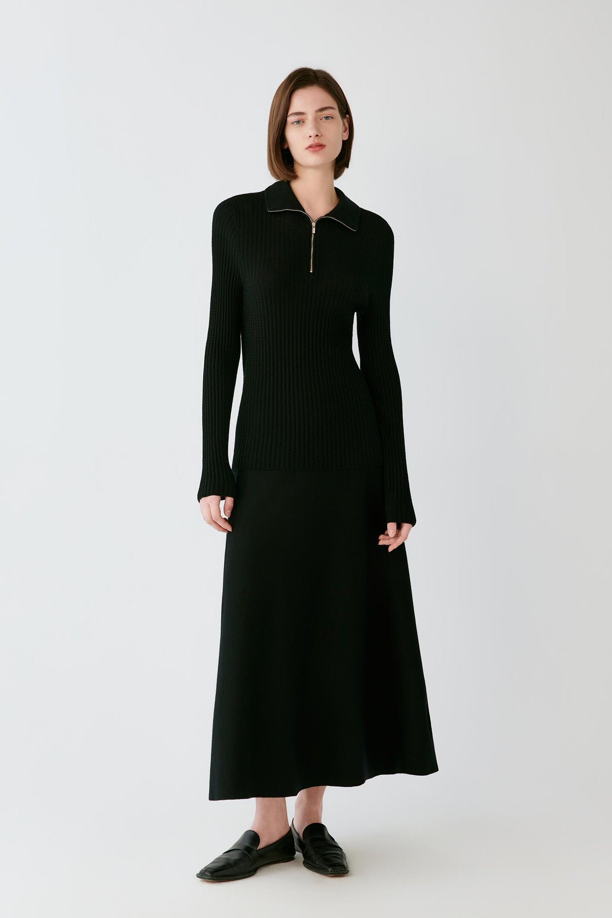 Front full-length view of a woman wearing the deep black worsted wool pullover, highlighting the long sleeves and fitted silhouette.