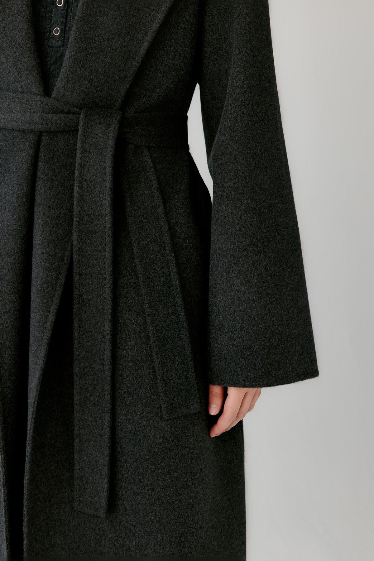 Close-up highlighting the self-tie belt, side pocket and melange texture of the double-face wool and cashmere coat.