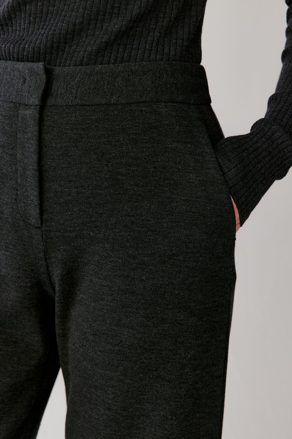 Close-up highlighting the side pocket, waistband and melange texture of the blended jersey trousers.