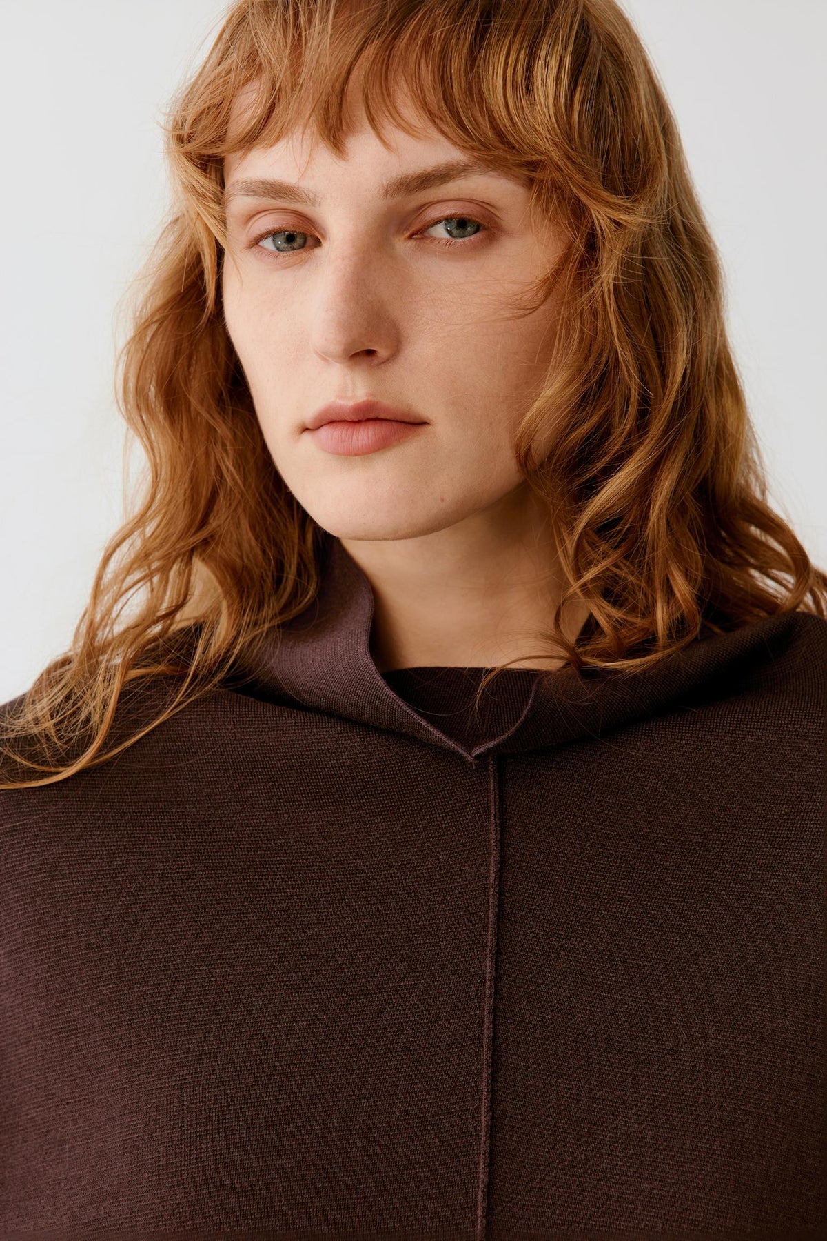 Close-up highlighting the mock neck and central seam of the dark brown merino wool pullover.