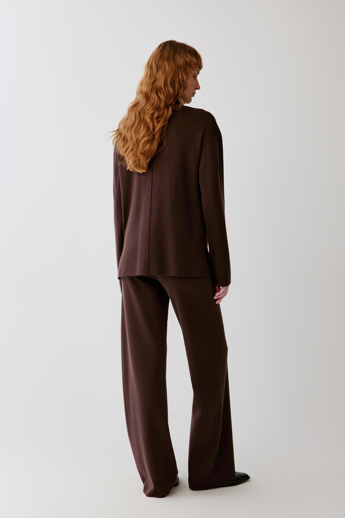 Three-quarter view showing the mock neck, dropped shoulders and smooth merino wool knit.