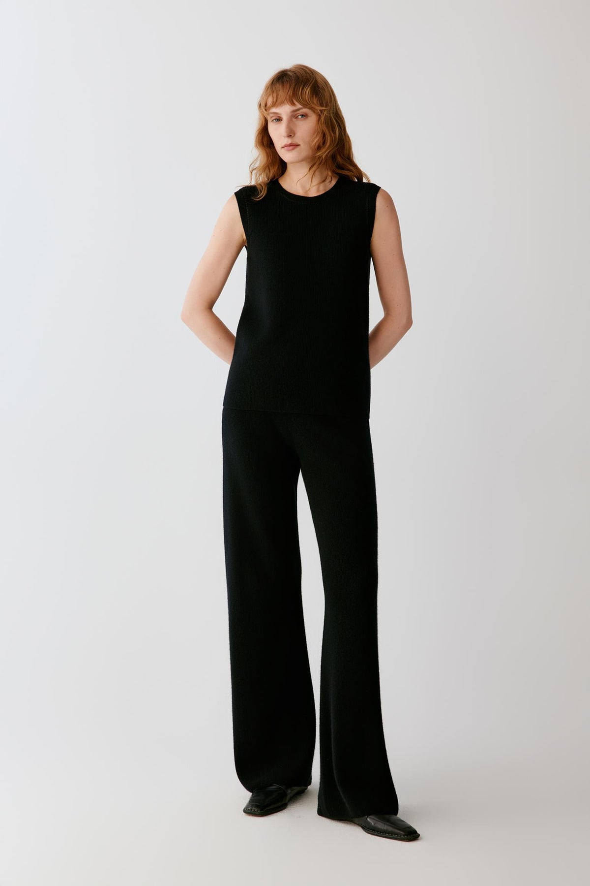 Front full-length view of a woman wearing the black cashmere trousers, highlighting the high-rise waist and straight-leg cut.