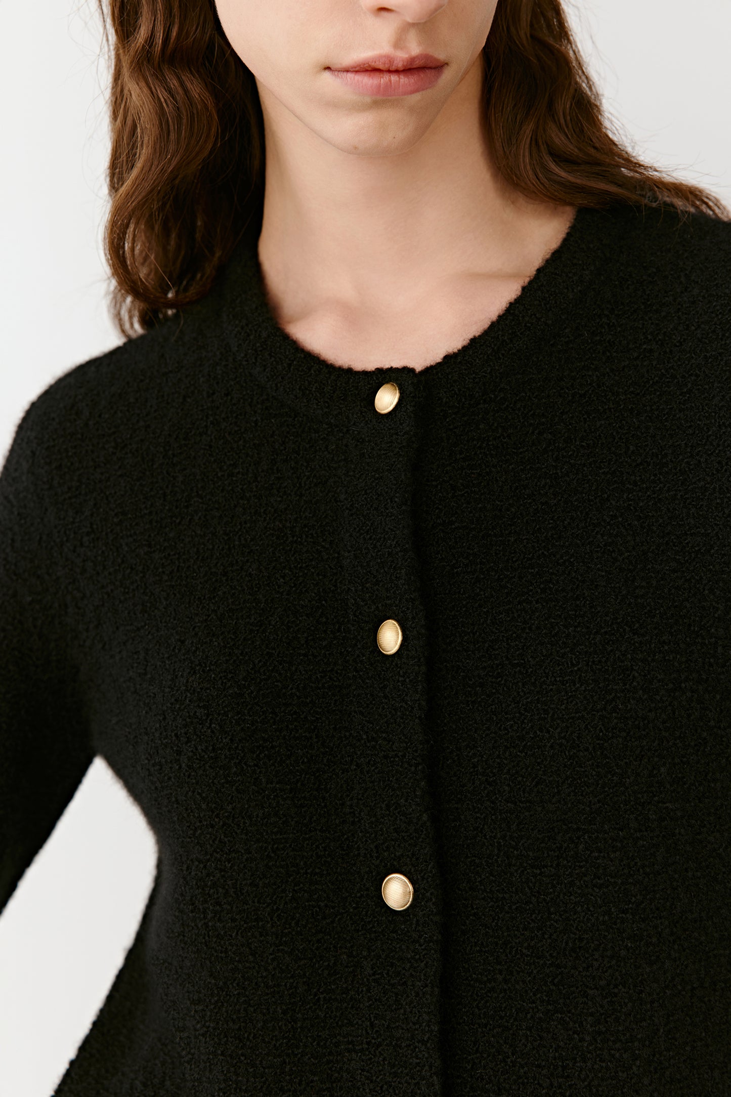 Close-up of the black cashmere cardigan’s neckline and metallic buttons, showing the fine knit texture and minimal detailing.