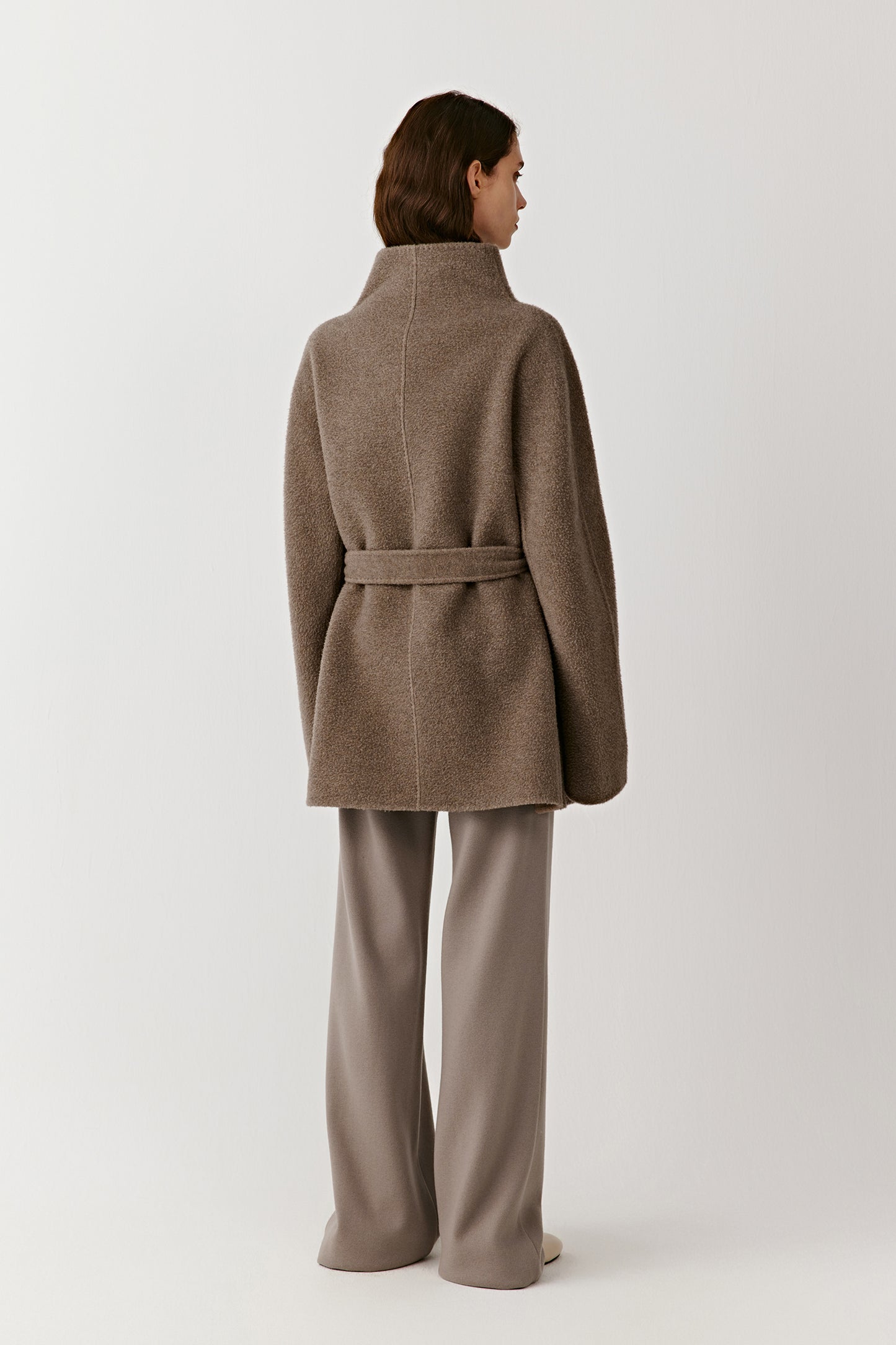 Full-body back view of the walnut brown cashmere coat, showing its straight cut and belt placement.