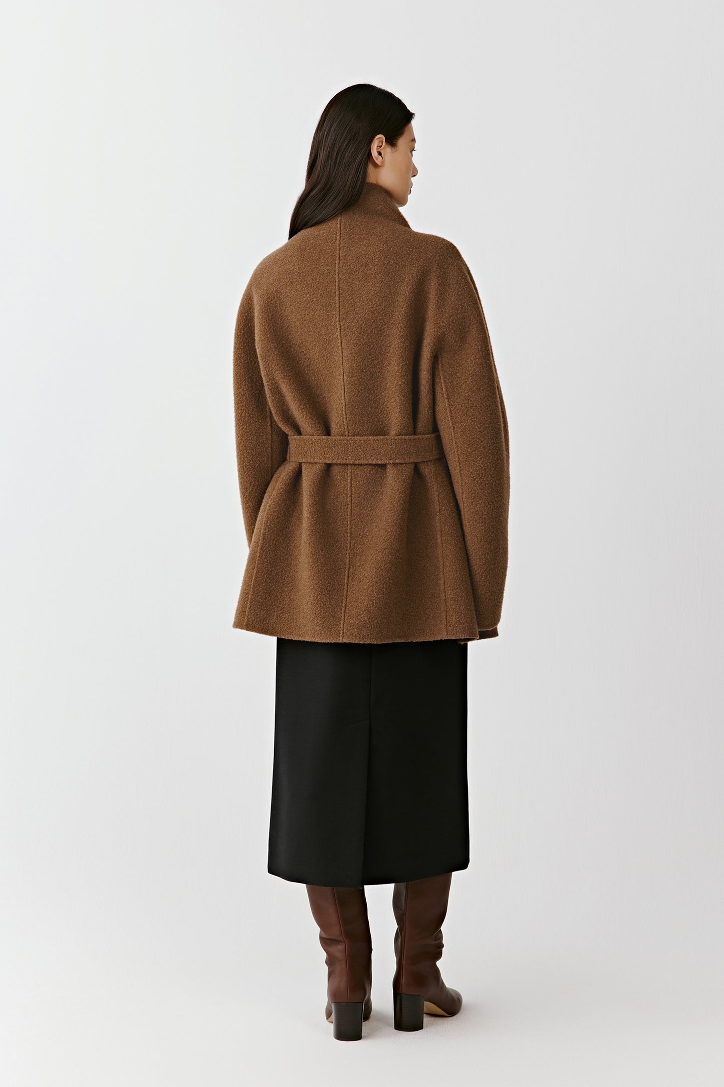 Back view of the camel and dark brown double-faced cashmere short coat, highlighting the straight silhouette, belt placement, and clean construction. The model is standing against a plain background.