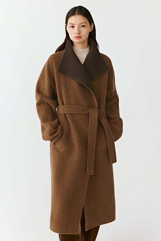 The model is seen at an angle, showing the coat’s smooth drape and the natural contrast between its two brown shades.