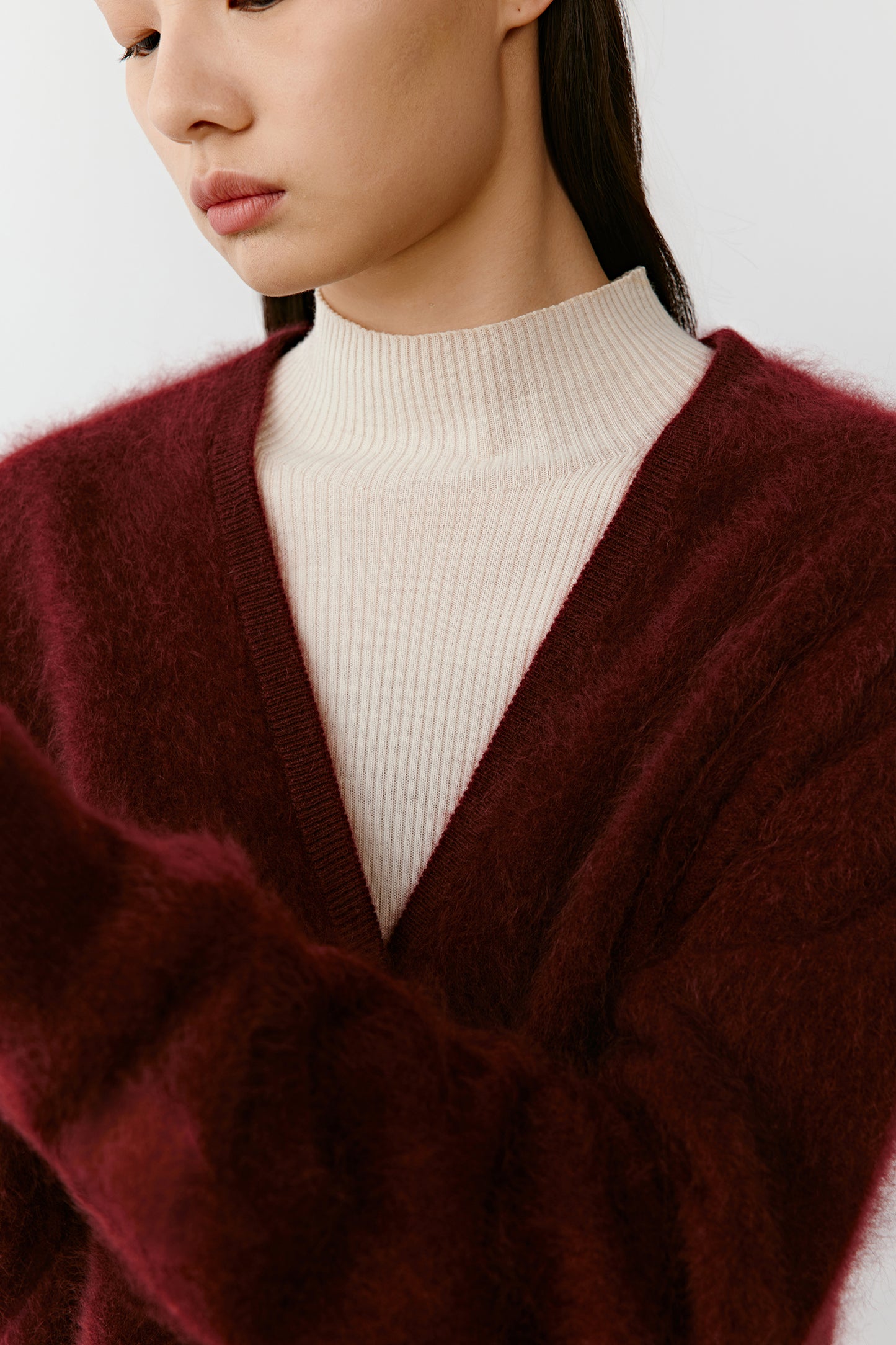Close-up of the deep red cashmere cardigan’s V-neckline and button detailing, revealing the brushed texture and rich color.