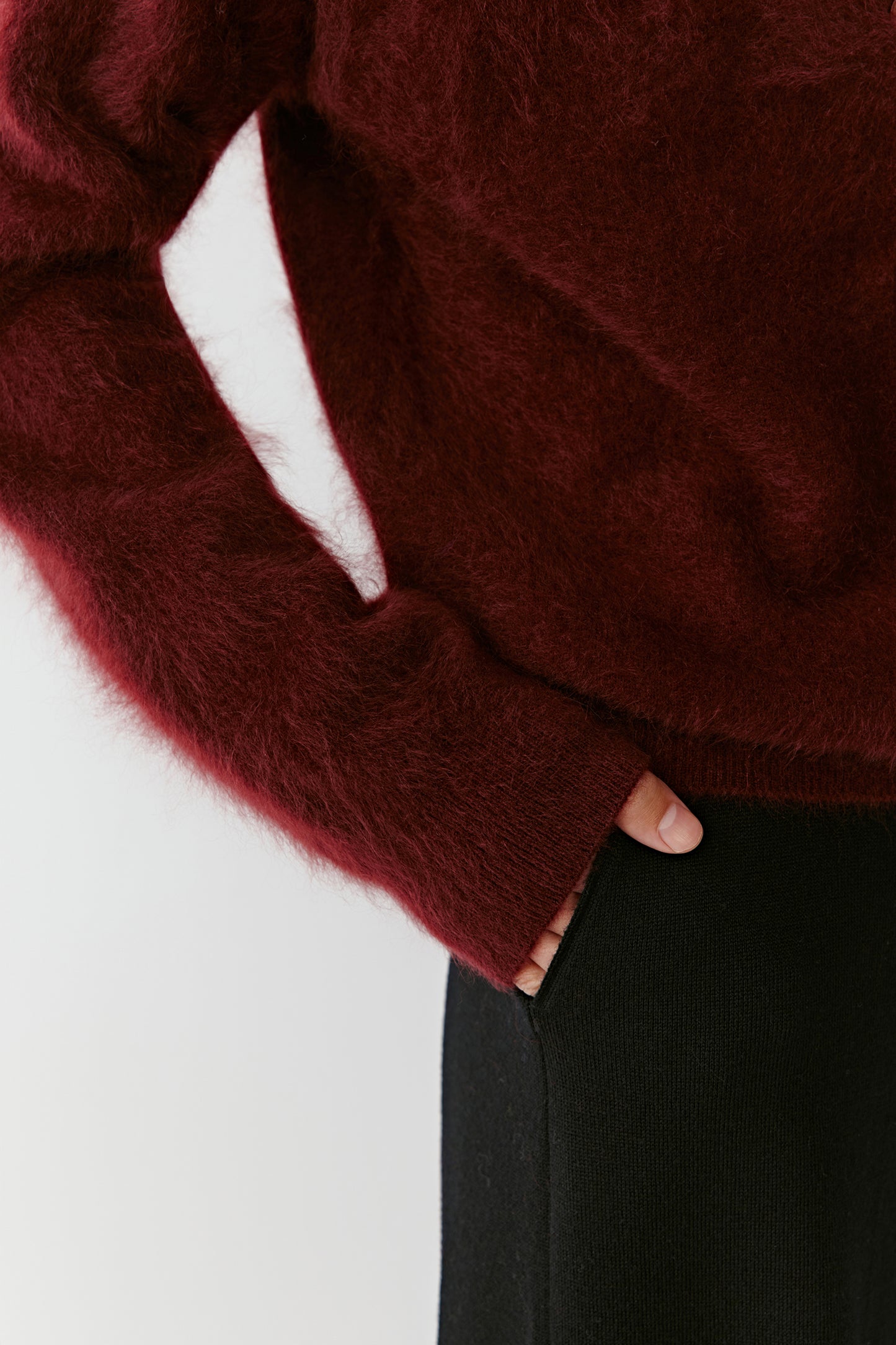 Close-up of the sleeve and torso area of the deep red cashmere cardigan, focusing on the soft knit texture and deep shade.
