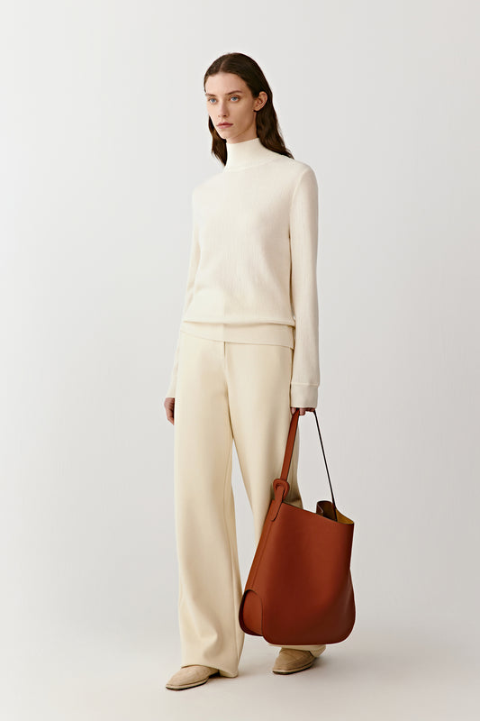 Full-length front view of straight-leg trousers in a cream cotton, silk and combed wool jersey blend, styled with a matching knit.