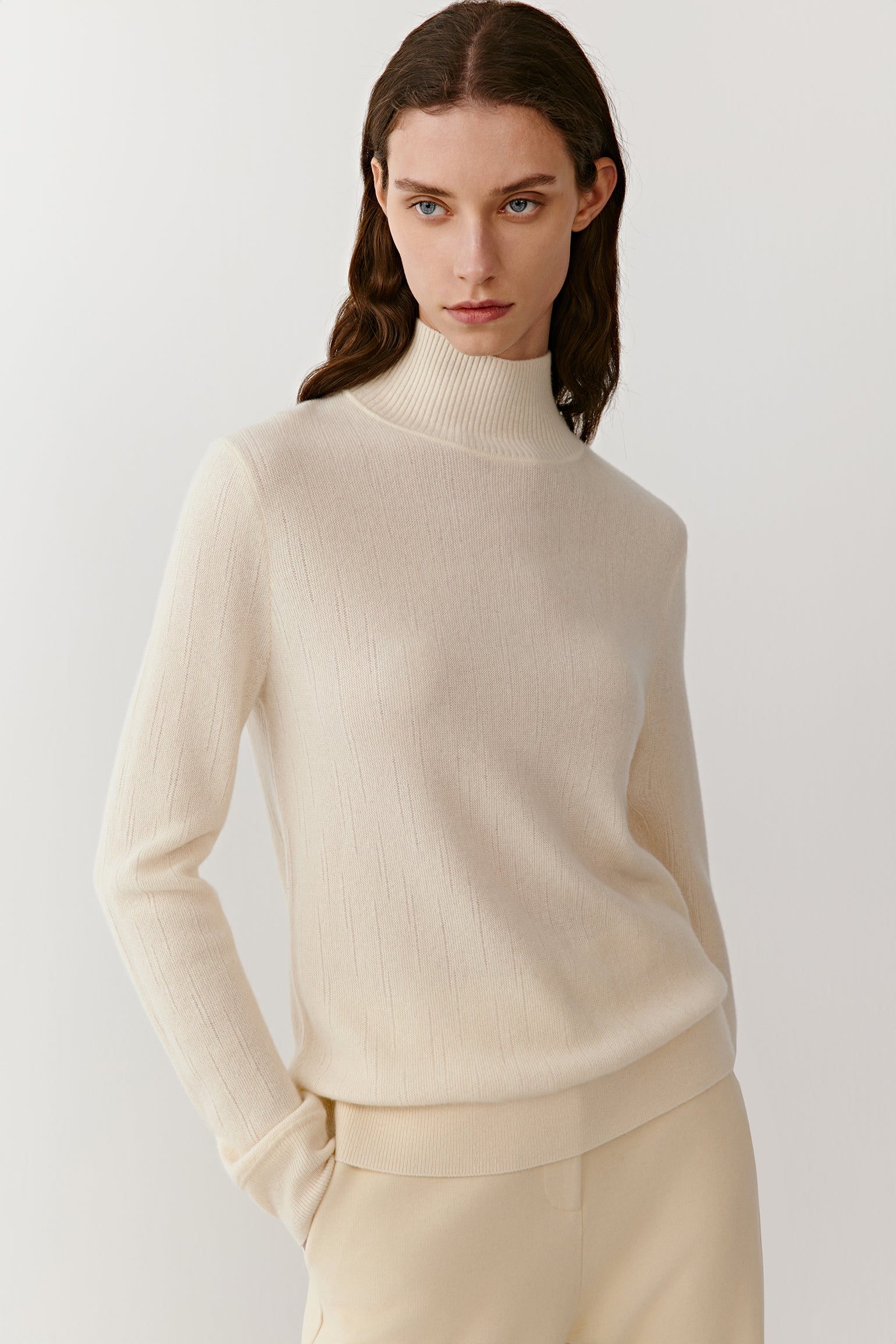 Three-quarter view of the cream cashmere pullover, highlighting clean lines, soft texture, and a relaxed fit.