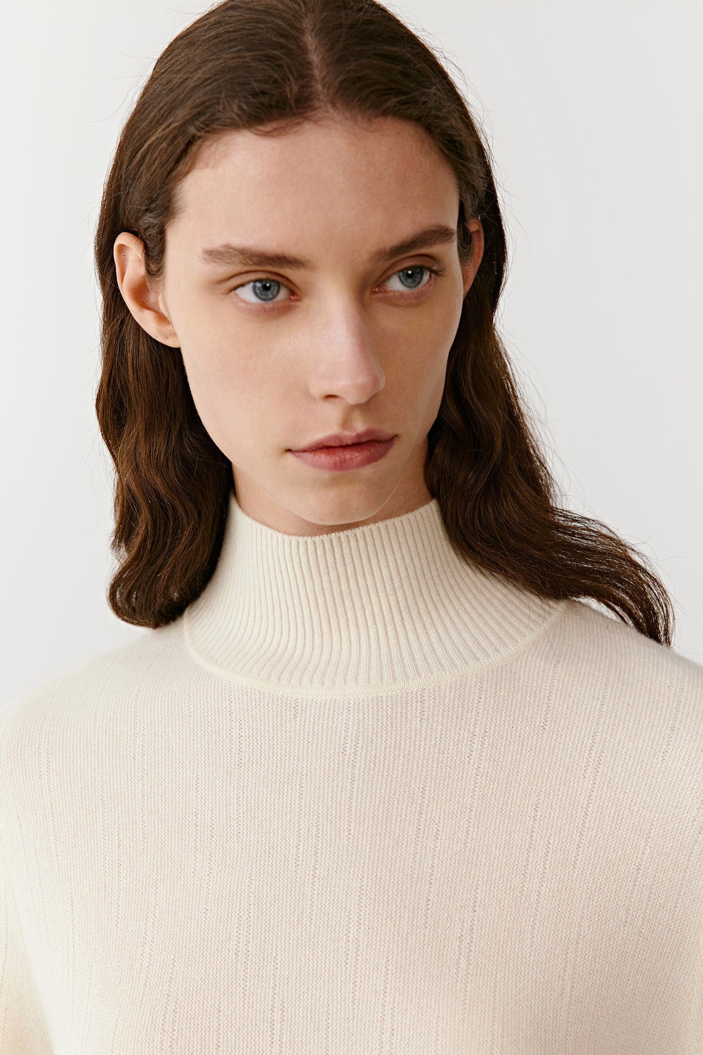 Close-up of the cream cashmere pullover’s high neckline, showing the fine knit and smooth finish.