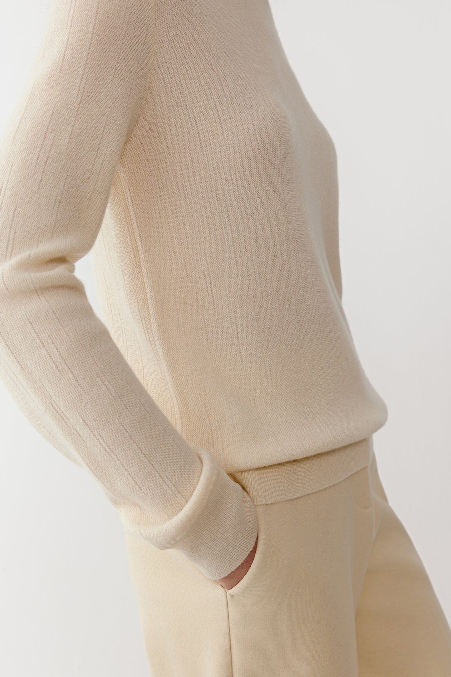 Detail close-up of the sleeve and hem of the cream cashmere pullover, highlighting the refined knit texture.