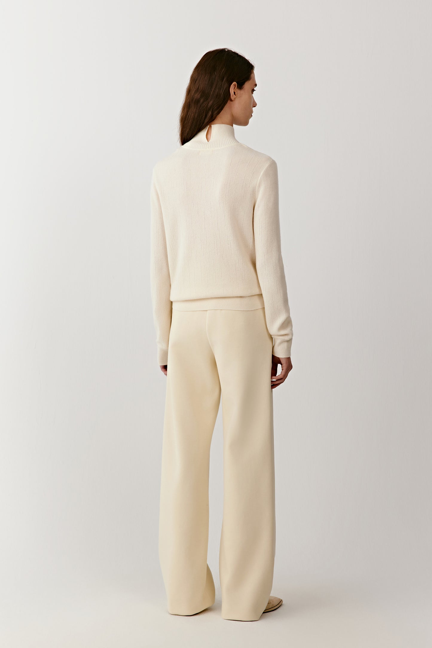 Back view of the high-neck cashmere pullover, showing a straight cut and a subtle slit detail at the back.