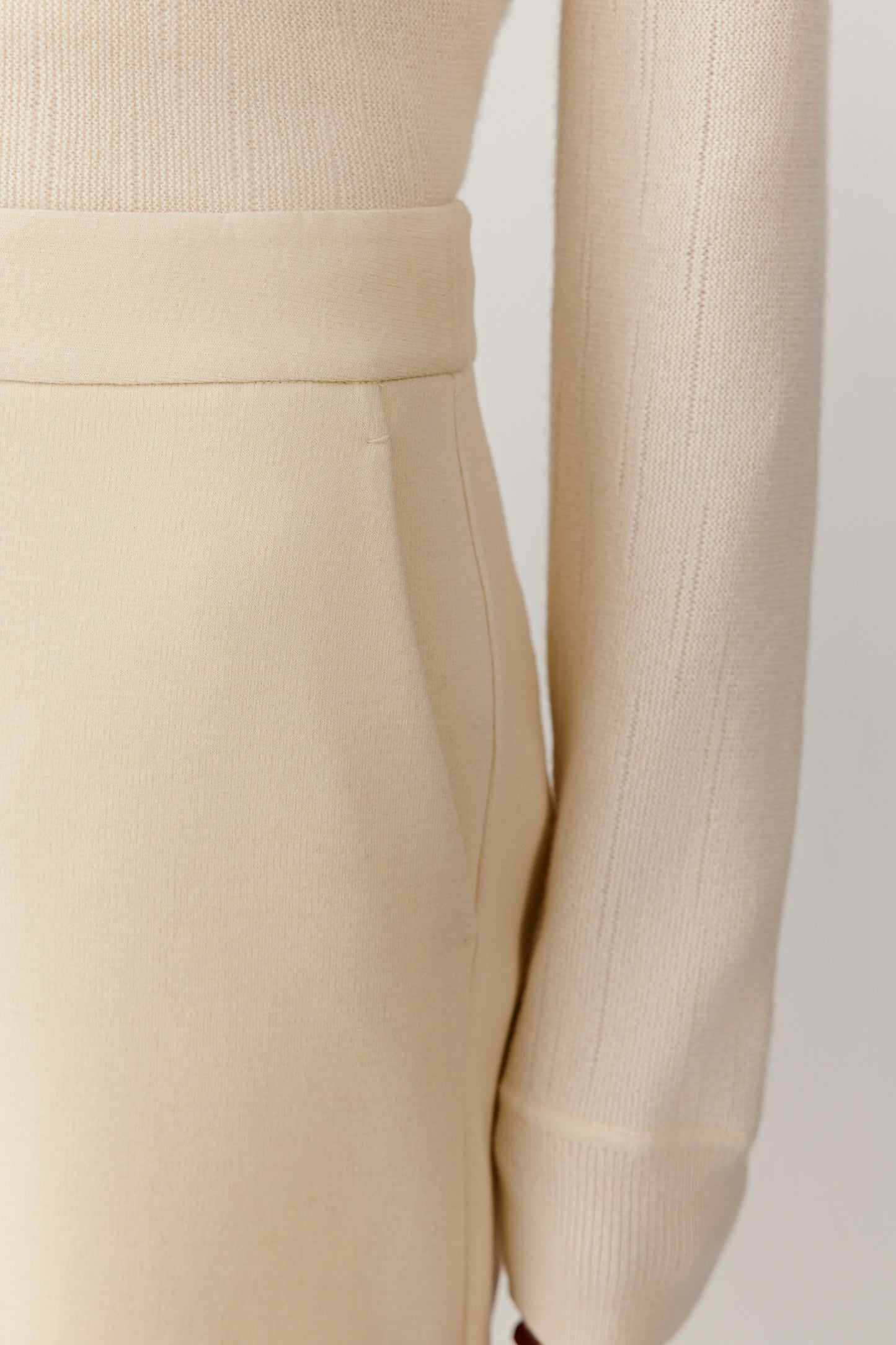Close-up of the discreet pocket detail on the cream jersey trousers.