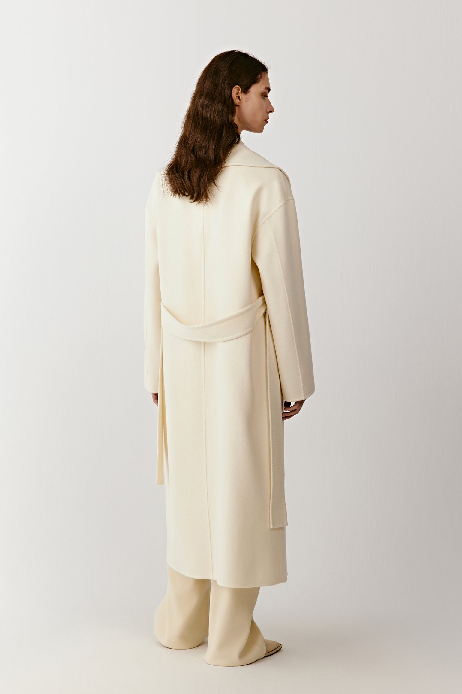 Side view of the long double-faced cashmere coat, highlighting clean lines and a soft drape.
