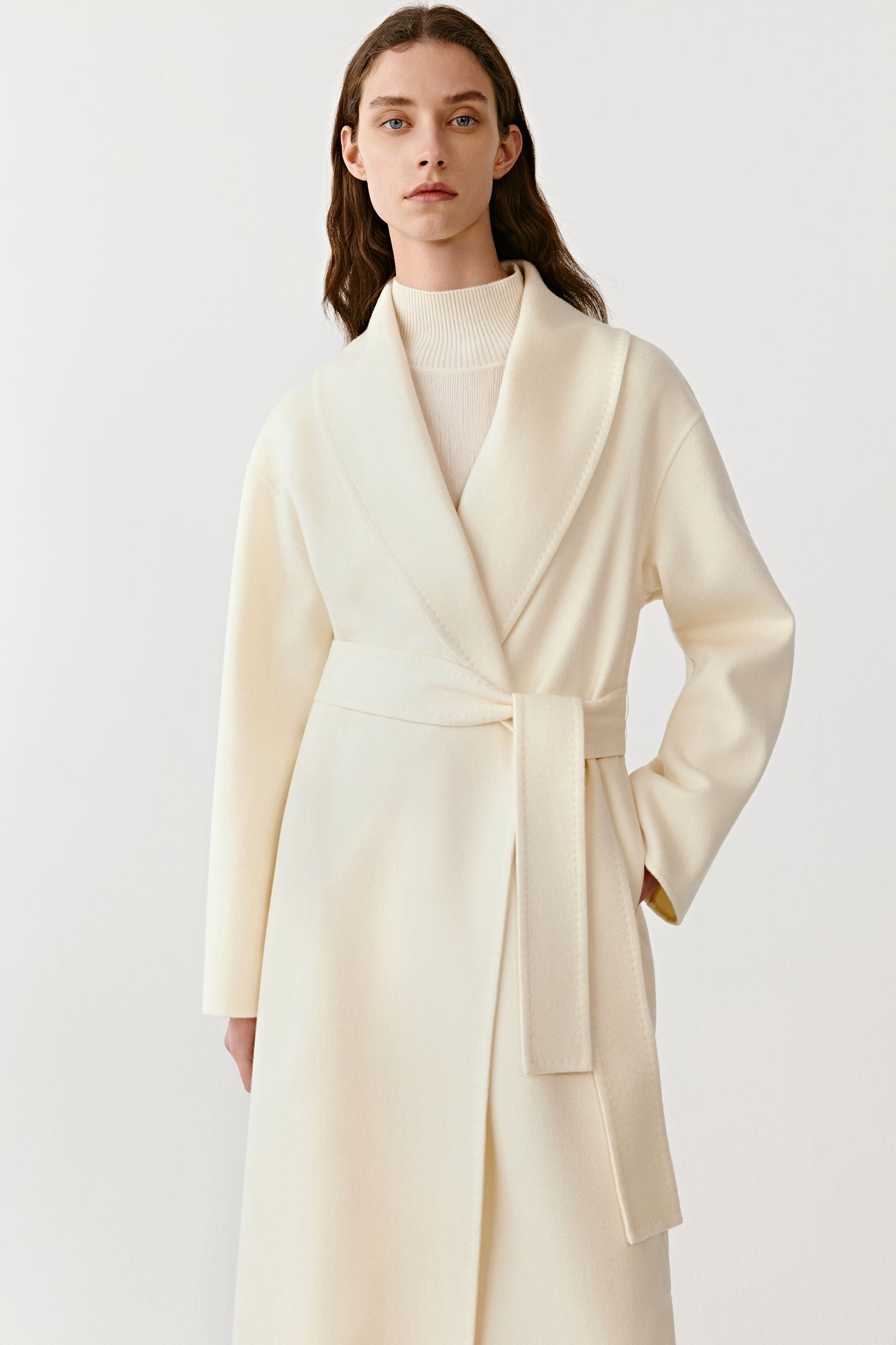 Three-quarter view of the shawl-collar cashmere coat, showing the belted waist and fluid silhouette.