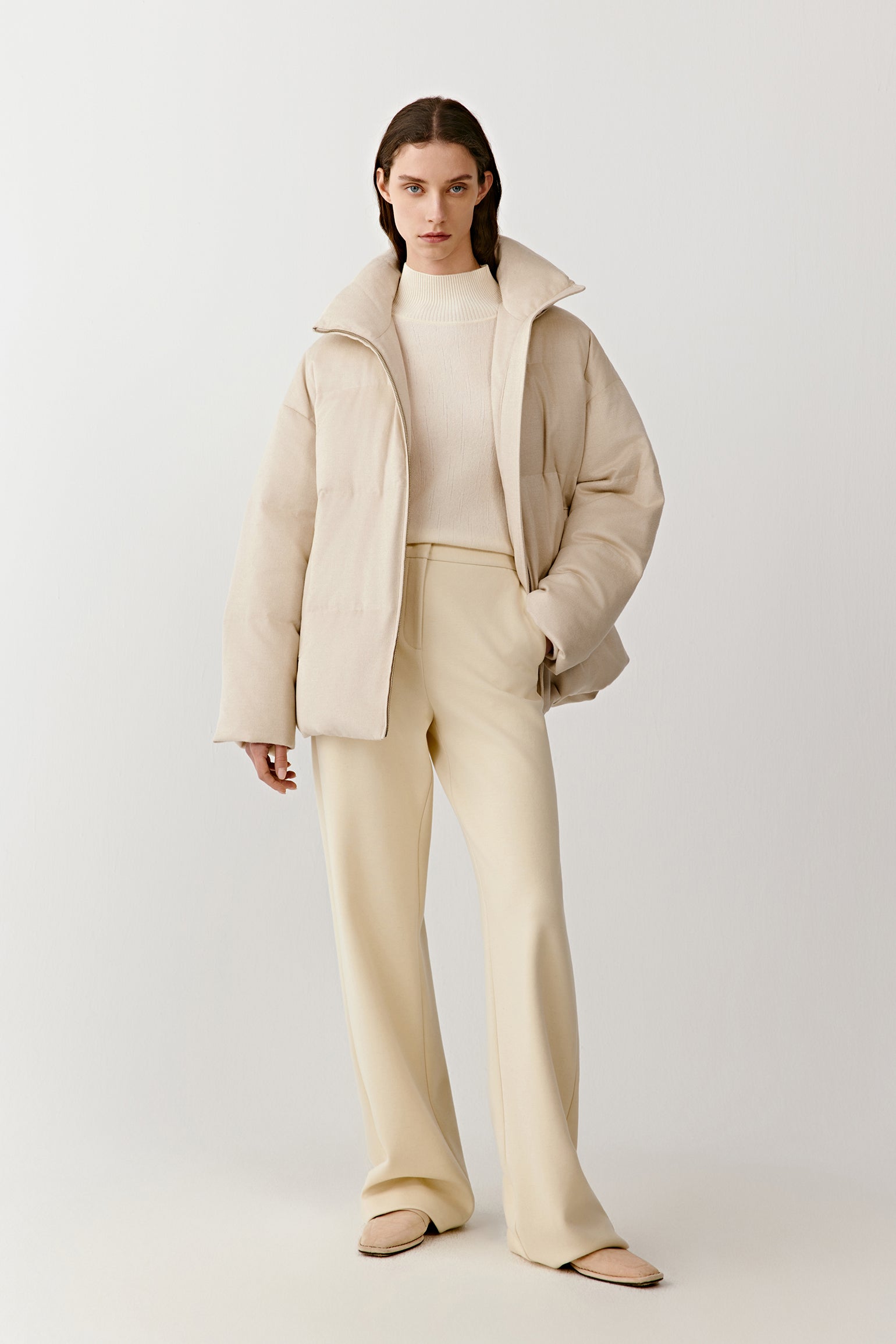 Full-length front view of a pale undyed silk down coat with a high stand collar and a clean padded silhouette.