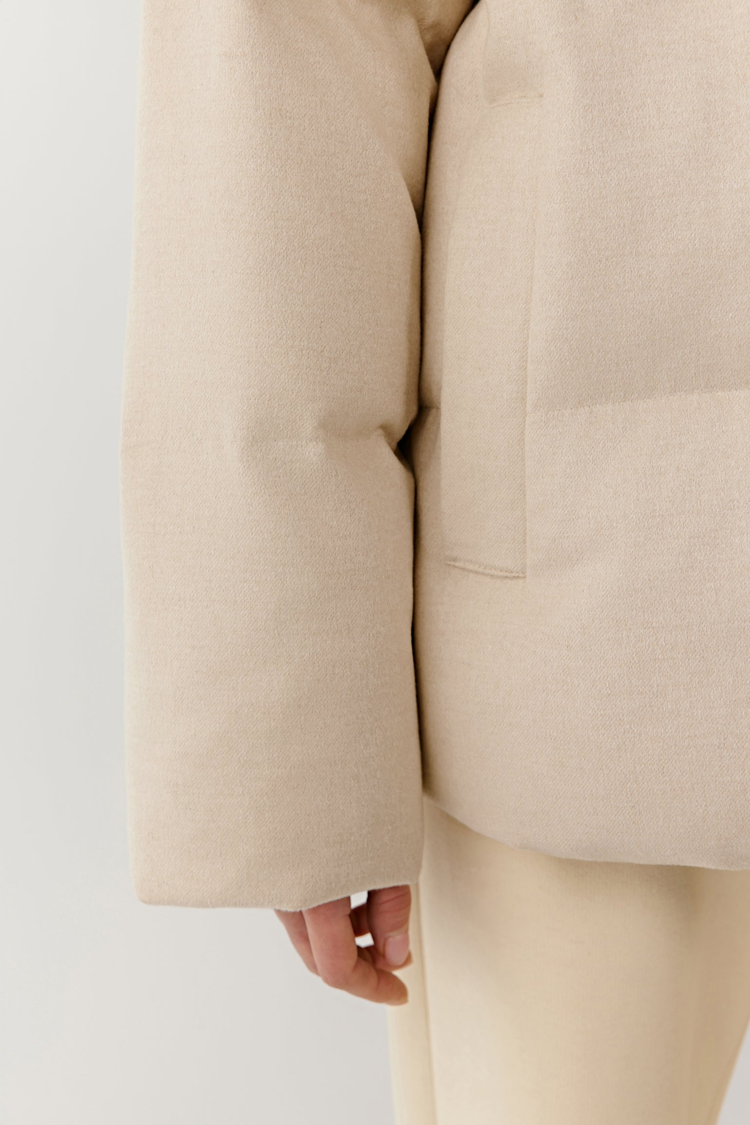 Detail close-up of the sleeve and padding of the undyed silk down coat.