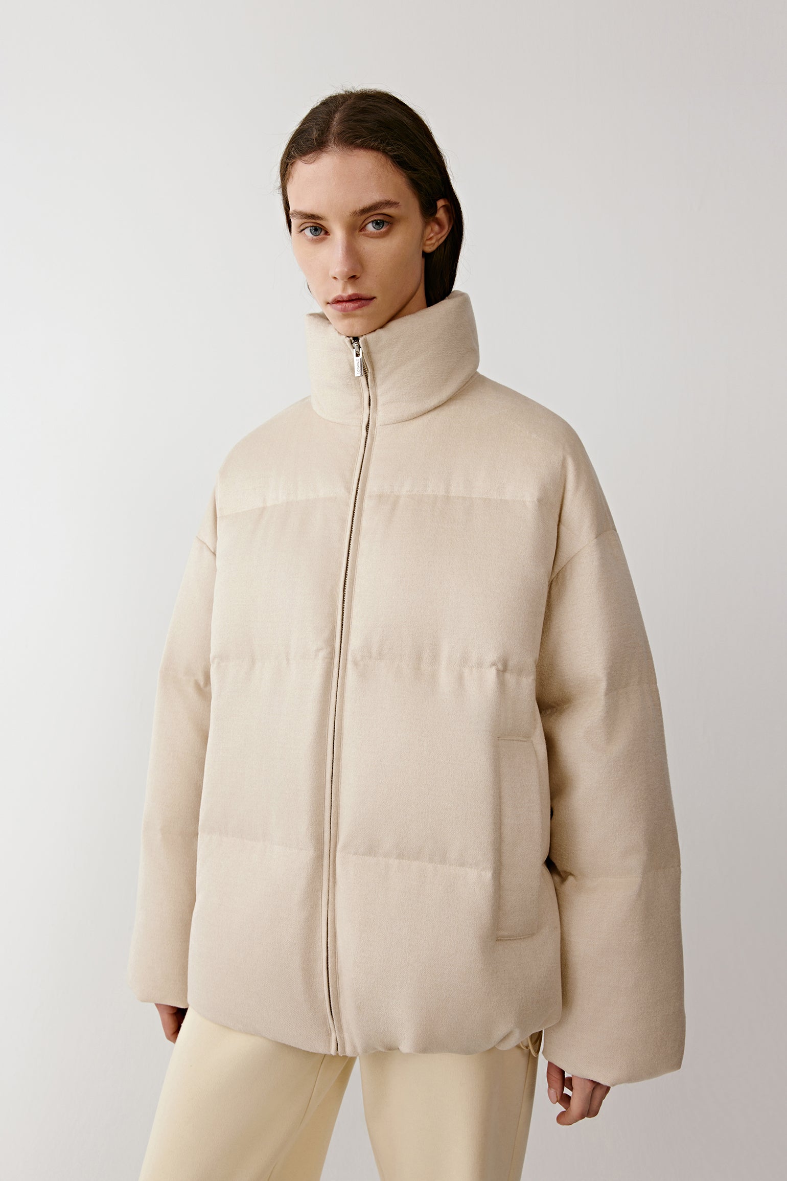 Three-quarter view of the undyed silk down coat, showing lightweight padding and a minimalist design.