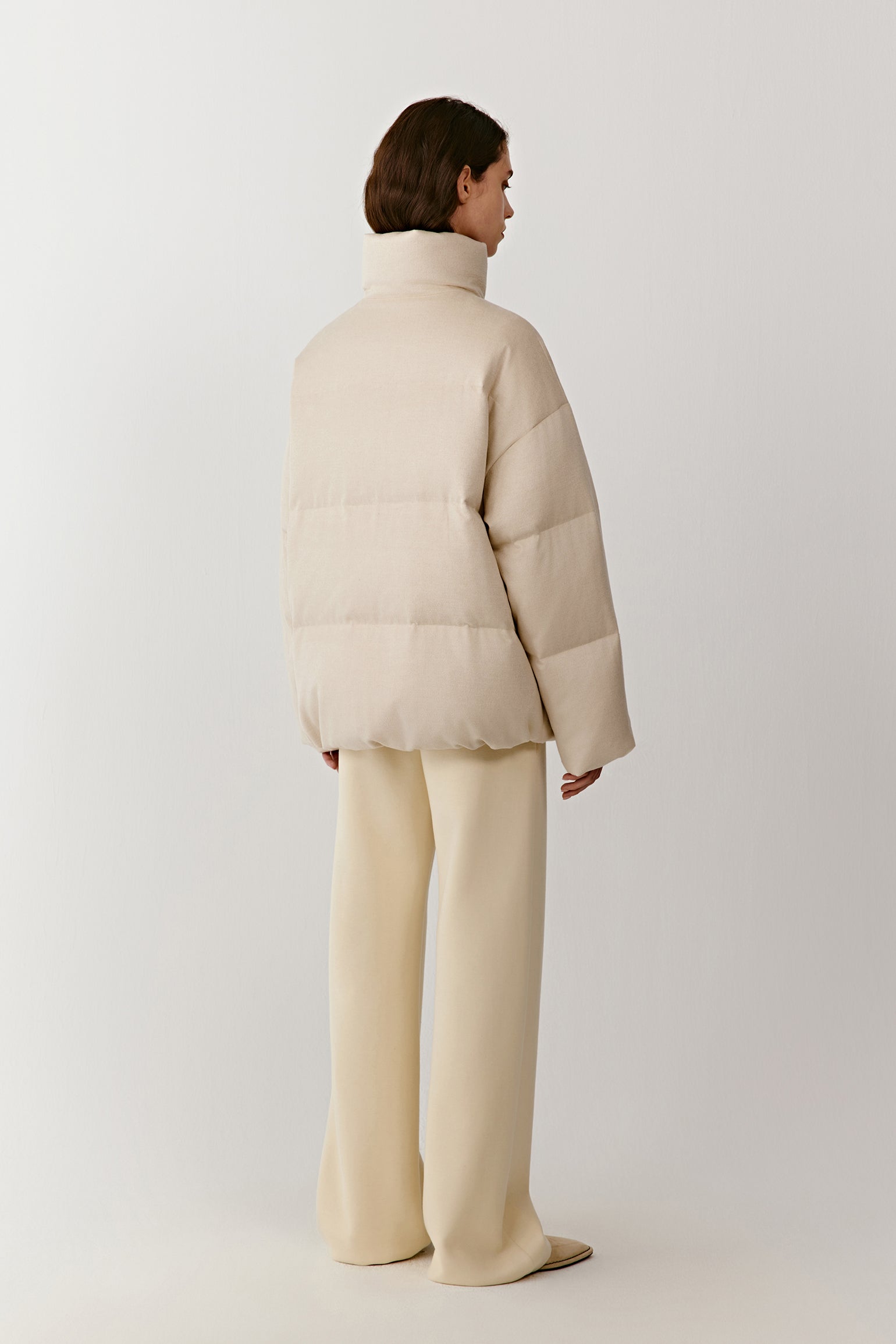 Back view of the undyed silk down coat, highlighting a straight cut and soft structure.