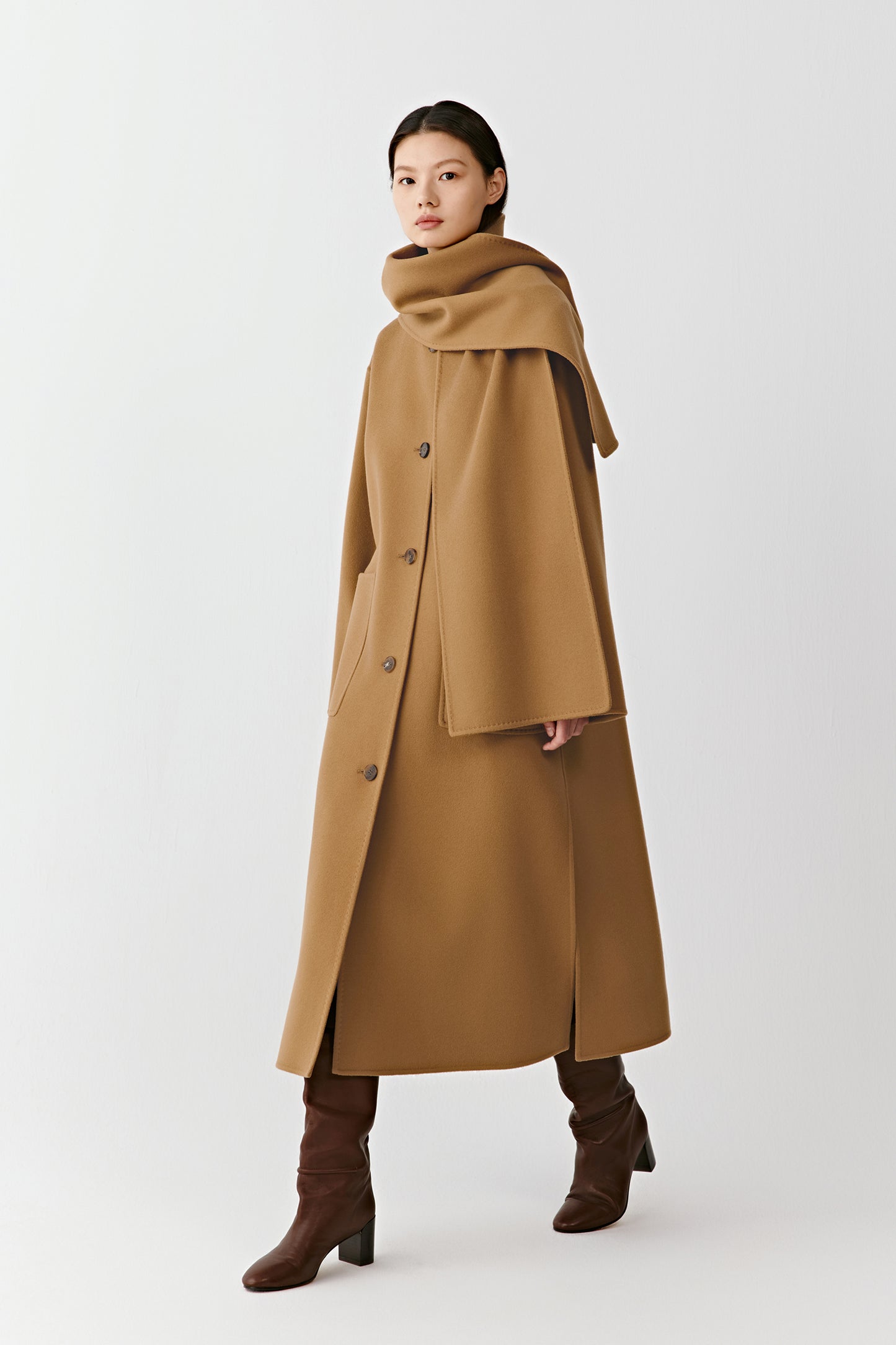 Full-length front view of a straight camel coat in double-faced wool and cashmere, featuring an integrated scarf and patch pockets.