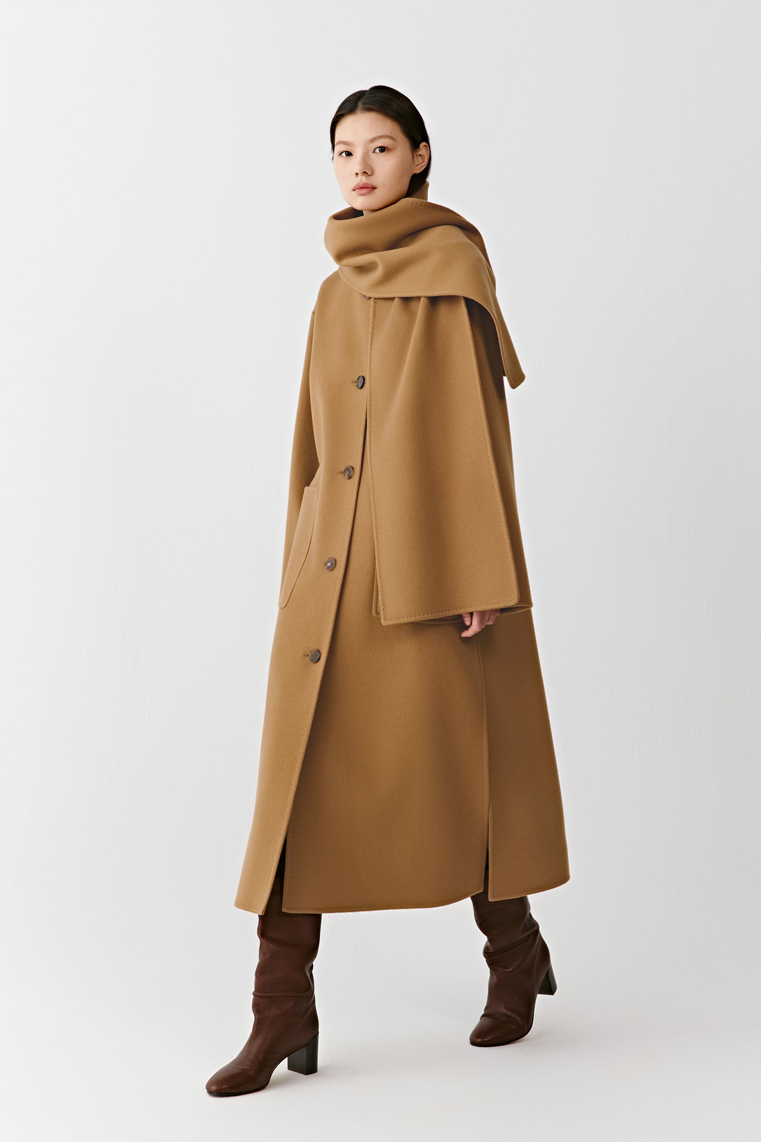 Full-length front view of a straight camel coat in double-faced wool and cashmere, featuring an integrated scarf and patch pockets.