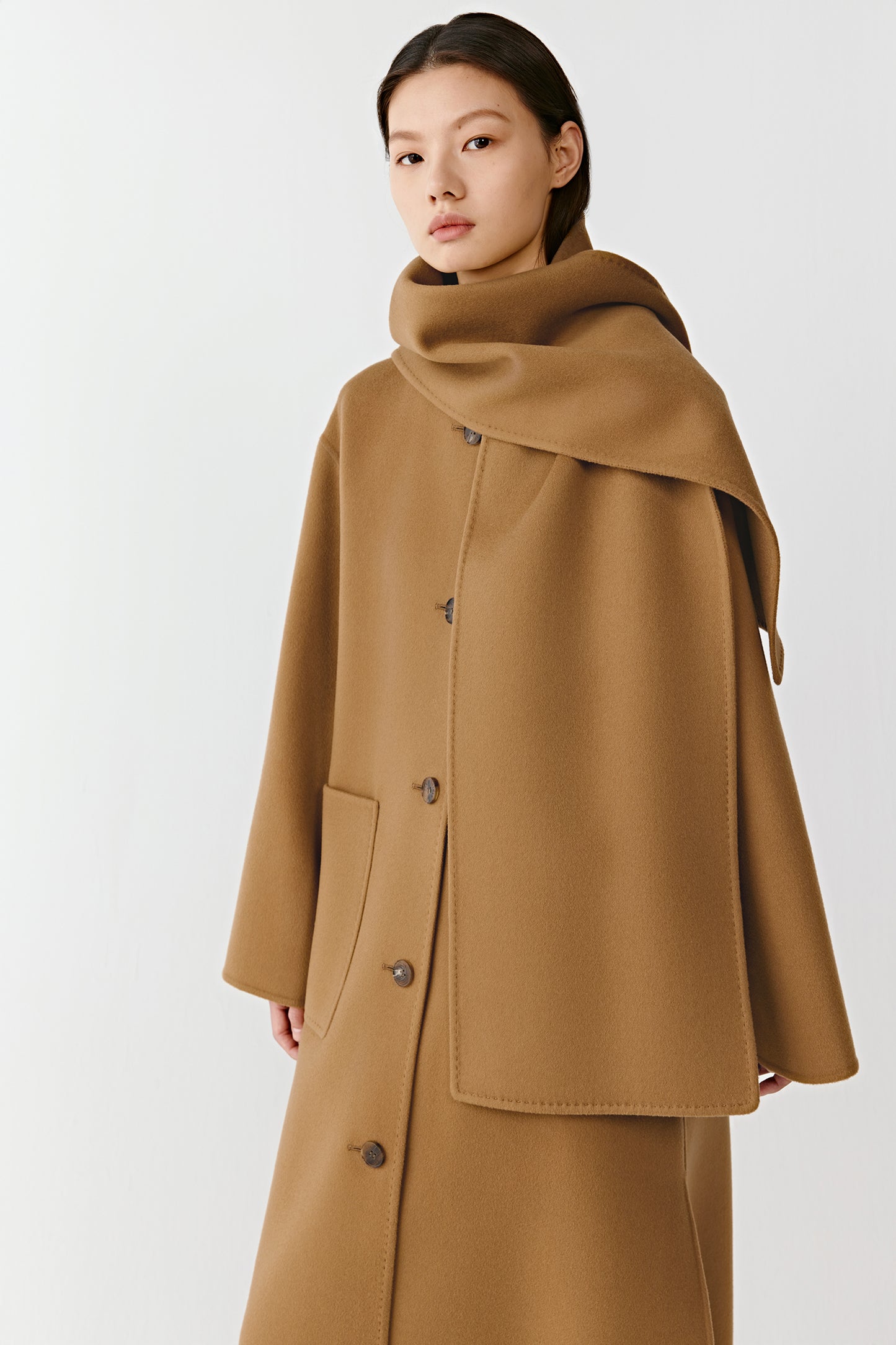 Three-quarter view of the camel double-faced coat, highlighting the integrated scarf and clean, structured lines.