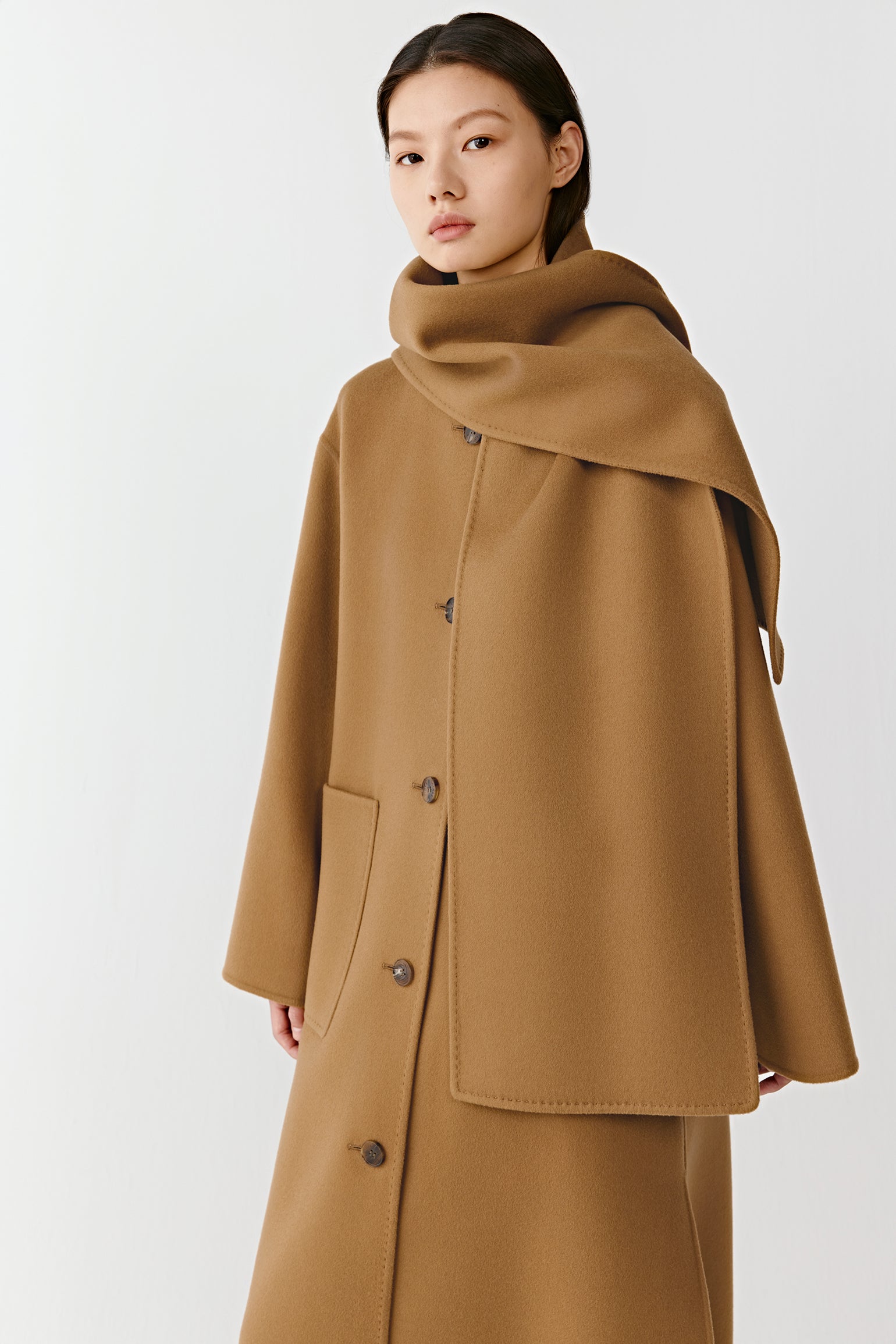 Three-quarter view of the camel double-faced coat, highlighting the integrated scarf and clean, structured lines.