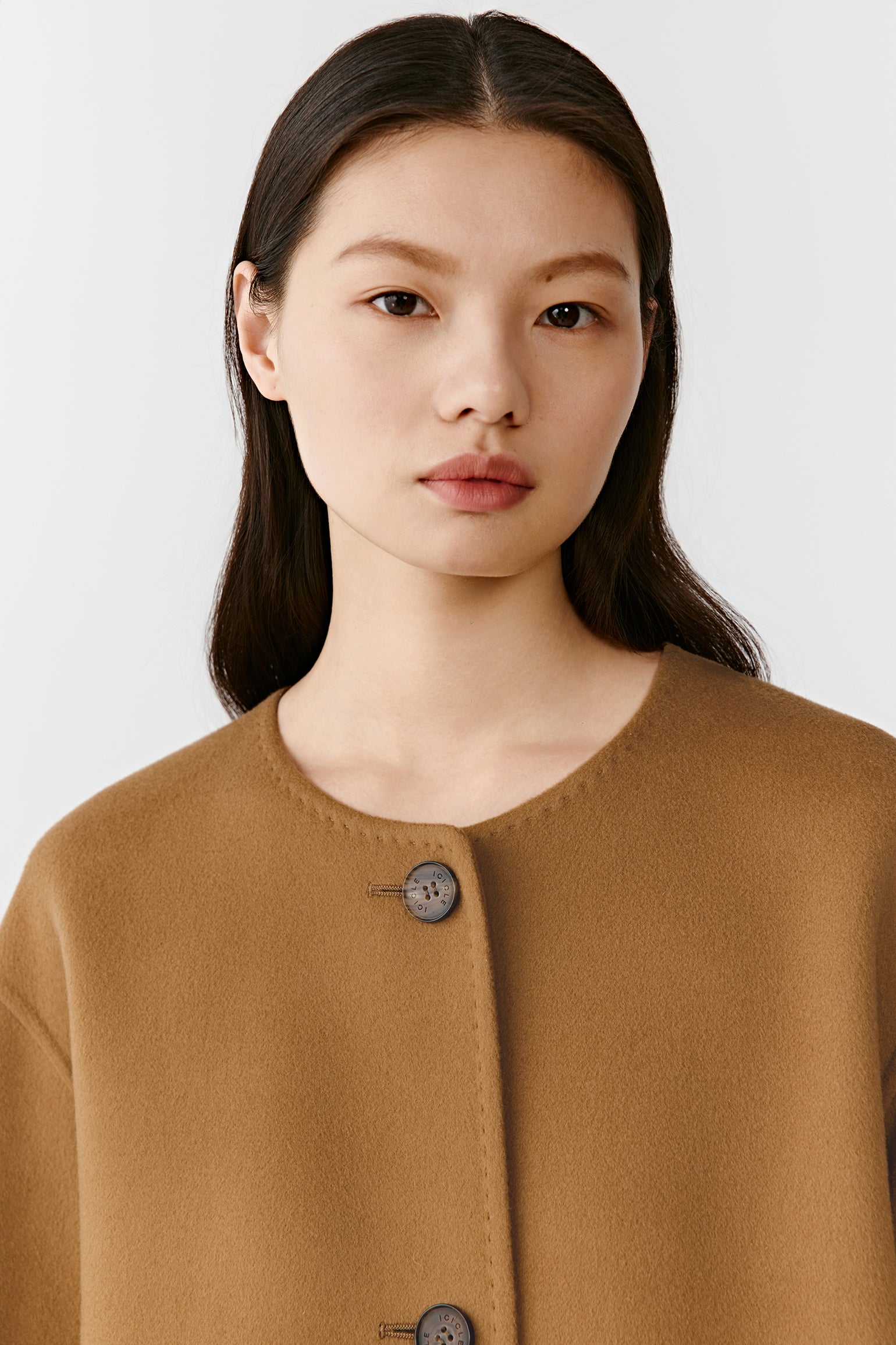 Close-up of the coat’s neckline and integrated scarf, highlighting the soft texture and natural camel shade.