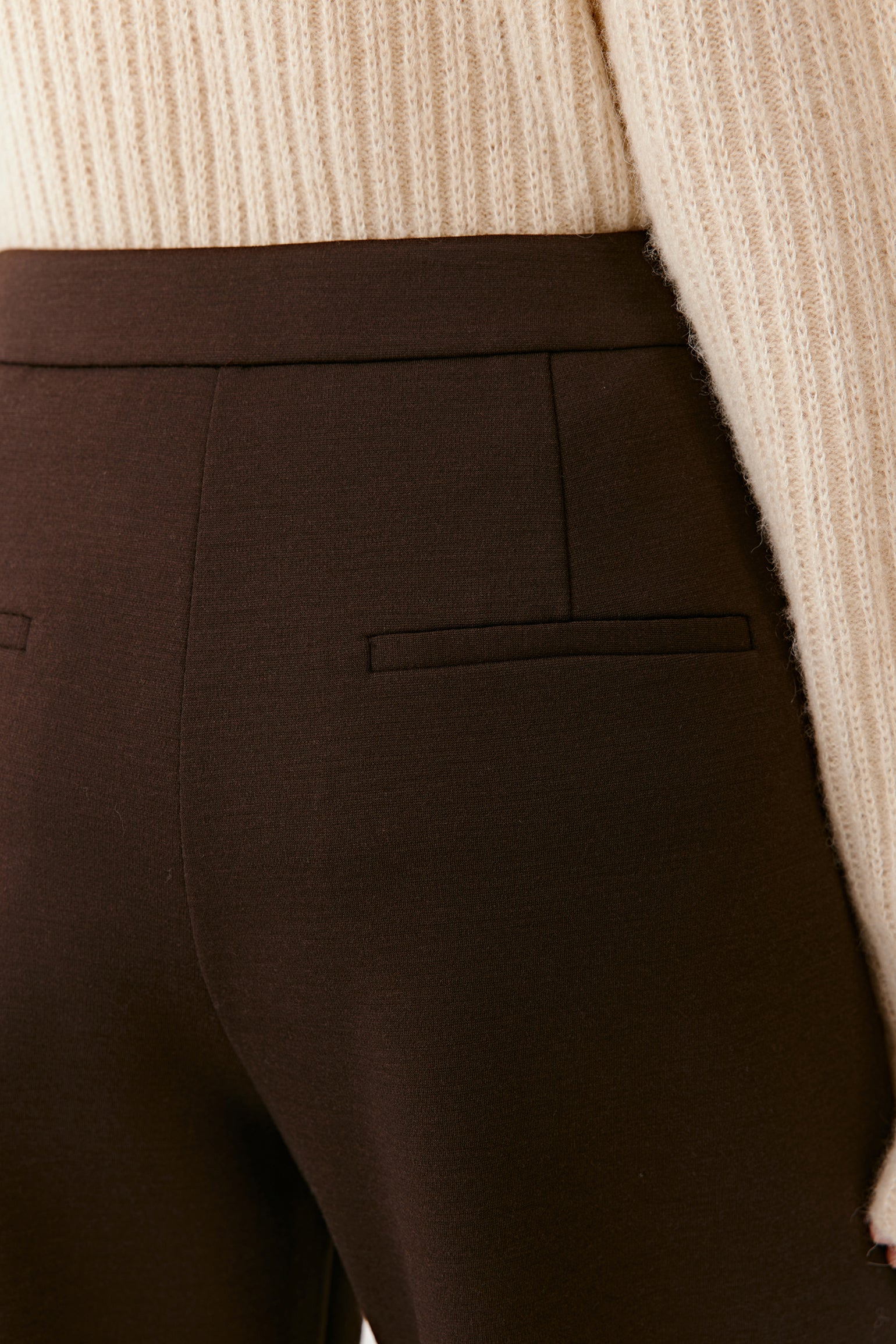 Detail close-up of the waistband and pressed crease of the straight-leg wool trousers.