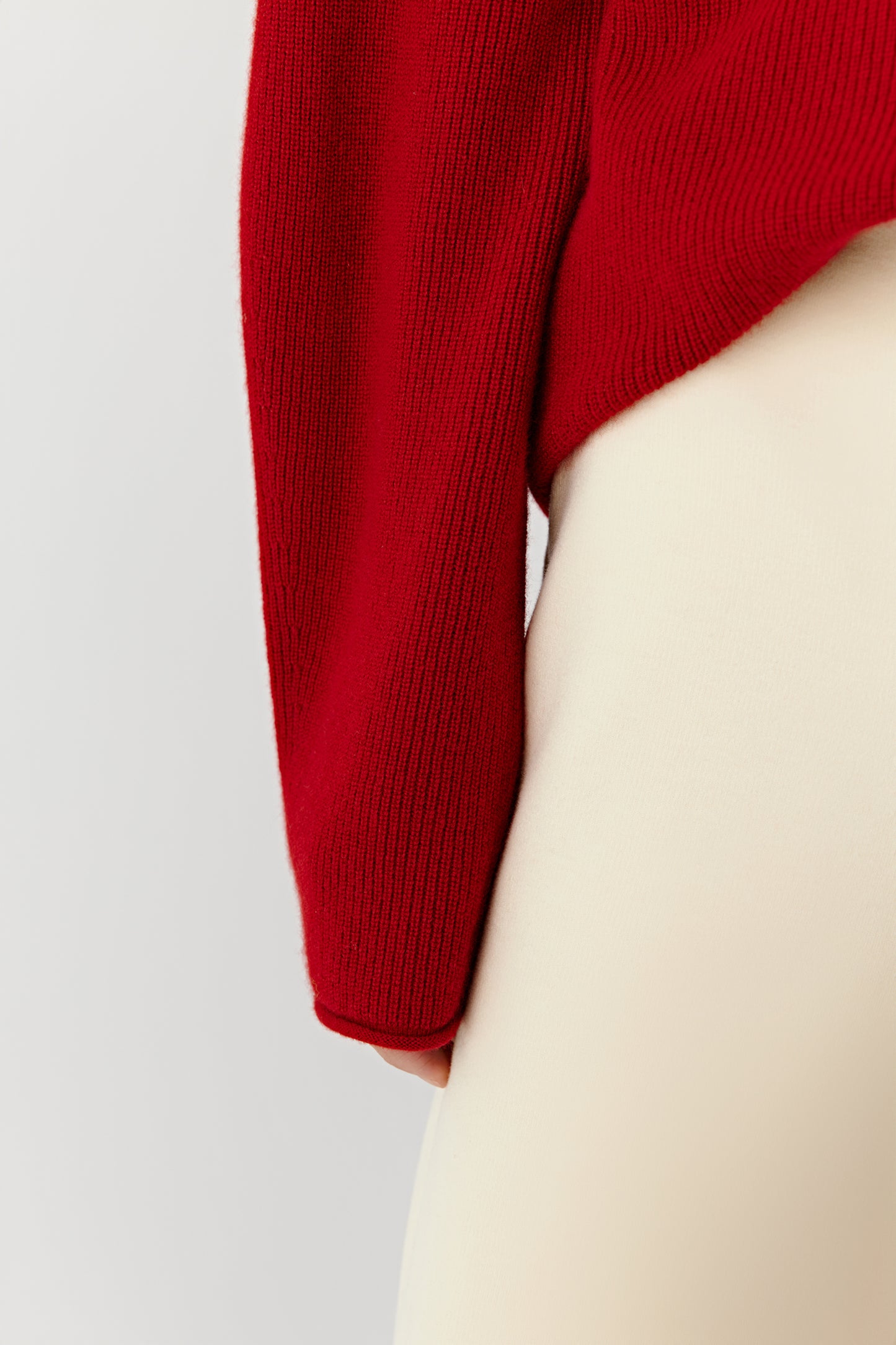 Detail close-up of the sleeve and cuff of the red cashmere pullover.