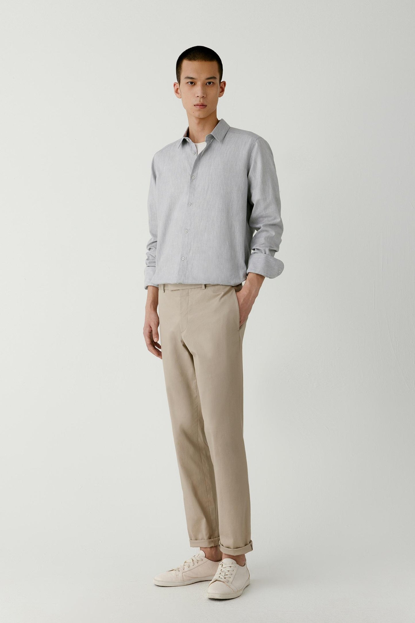 Man wearing a light grey melange cotton straight-fit shirt, styled with beige trousers, full-length front view.