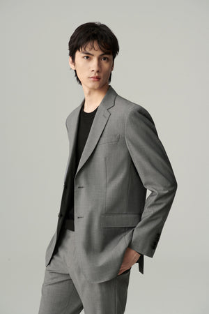 Man wearing a light grey straight-fit merino wool blazer with matching trousers, styled with a black T-shirt, three-quarter front view.