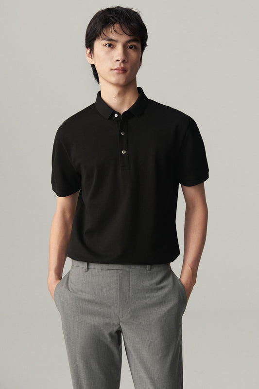 Front view of a man wearing a deep black silk polo, showing the straight silhouette, polo collar and three-button placket.