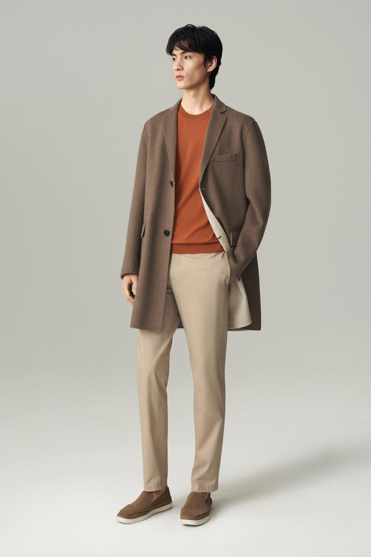 Front view of a man wearing a dark brown cashmere and wool coat, showing the long straight silhouette and notched lapels.