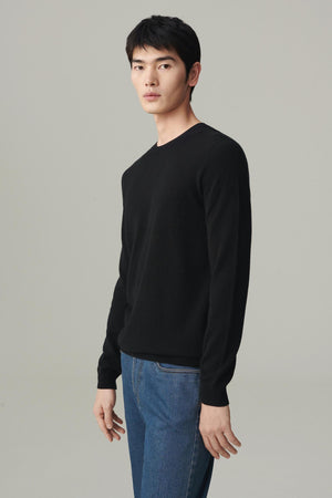 Front view of a man wearing a deep black cashmere pullover, showing the straight silhouette and crew neckline.