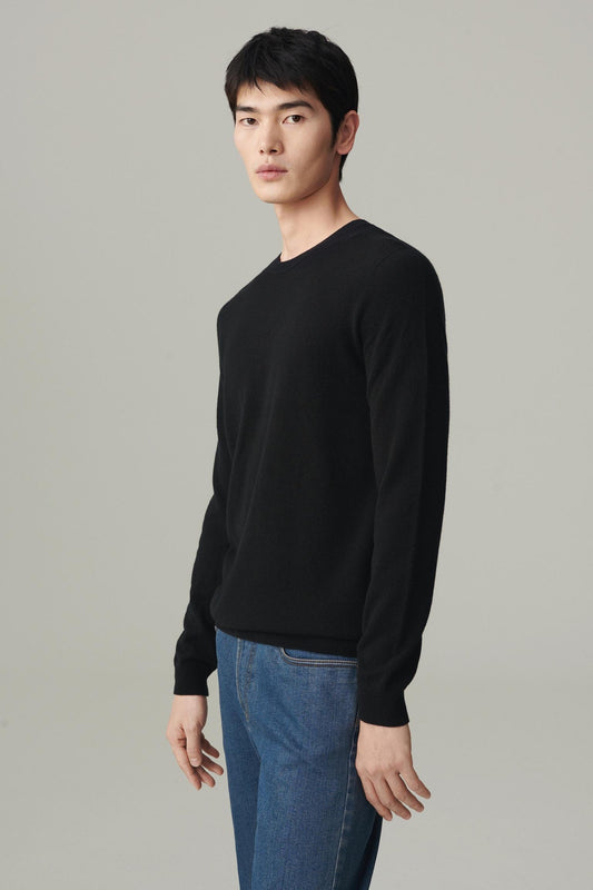 Front view of a man wearing a deep black cashmere pullover, showing the straight silhouette and crew neckline.