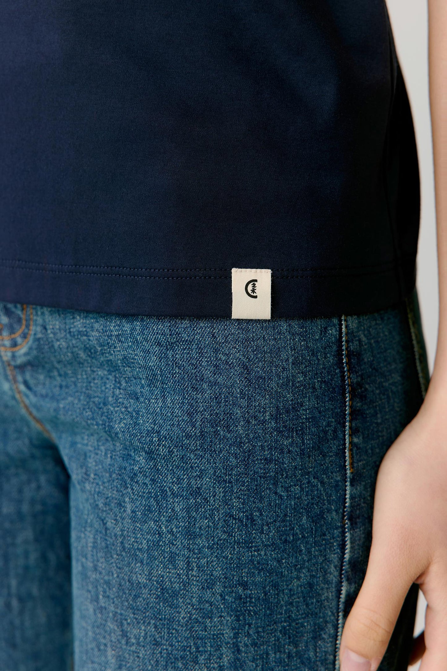 Close-up of the navy cotton jersey fabric, revealing a smooth, lightweight knit with a matte finish.