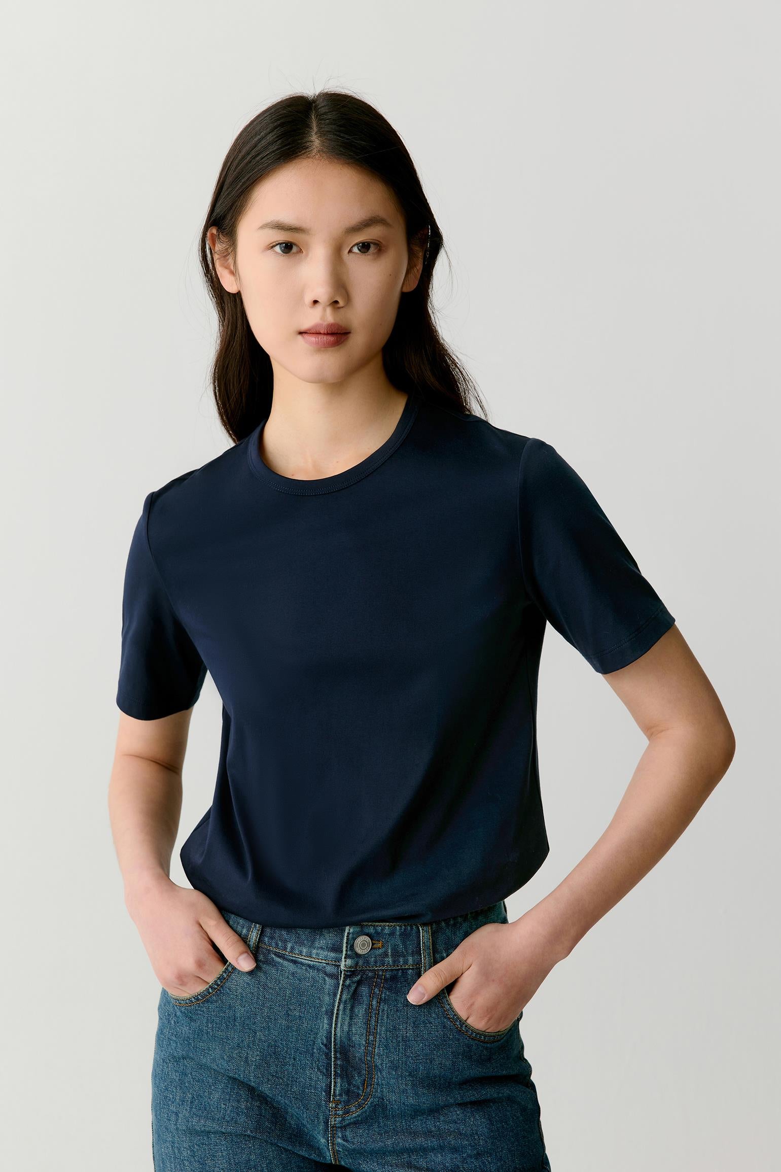Three-quarter front view of the navy cotton jersey T-shirt, highlighting the fluid drape of the fabric and the clean shoulder and sleeve lines.