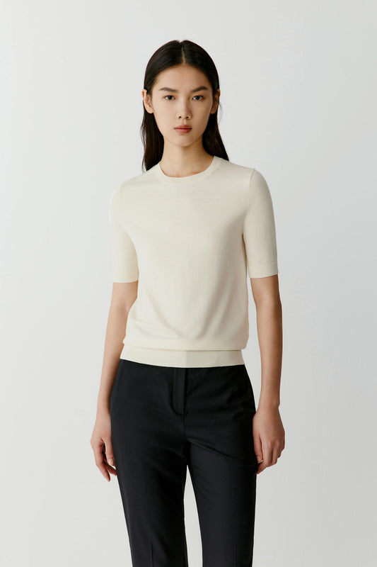 Three-quarter view highlighting the soft structure of the neckline and the fluid silhouette created by the lightweight wool knit.