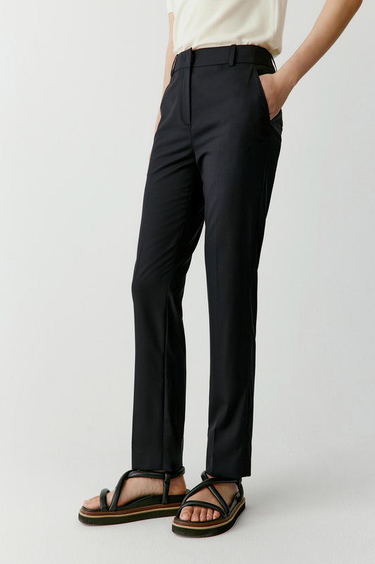 Three-quarter view showing the slightly tapered leg and side profile of the black worsted wool trousers.