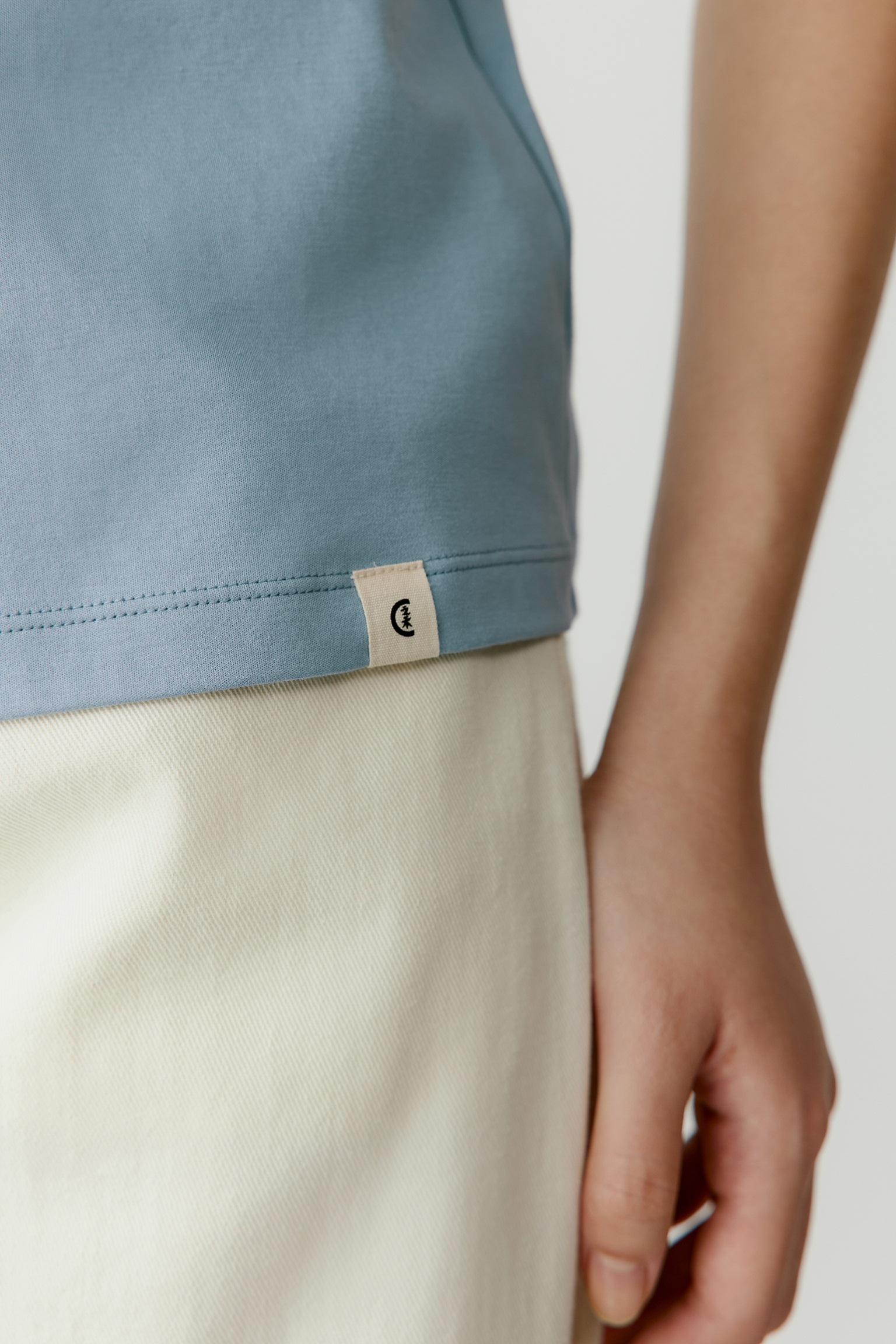 Close-up of the sleeve and side seam area, emphasizing the lightweight jersey construction, smooth surface and refined finishing. The image reveals the soft drape of the cotton fabric, its subtle tonal depth and the understated character of the design.