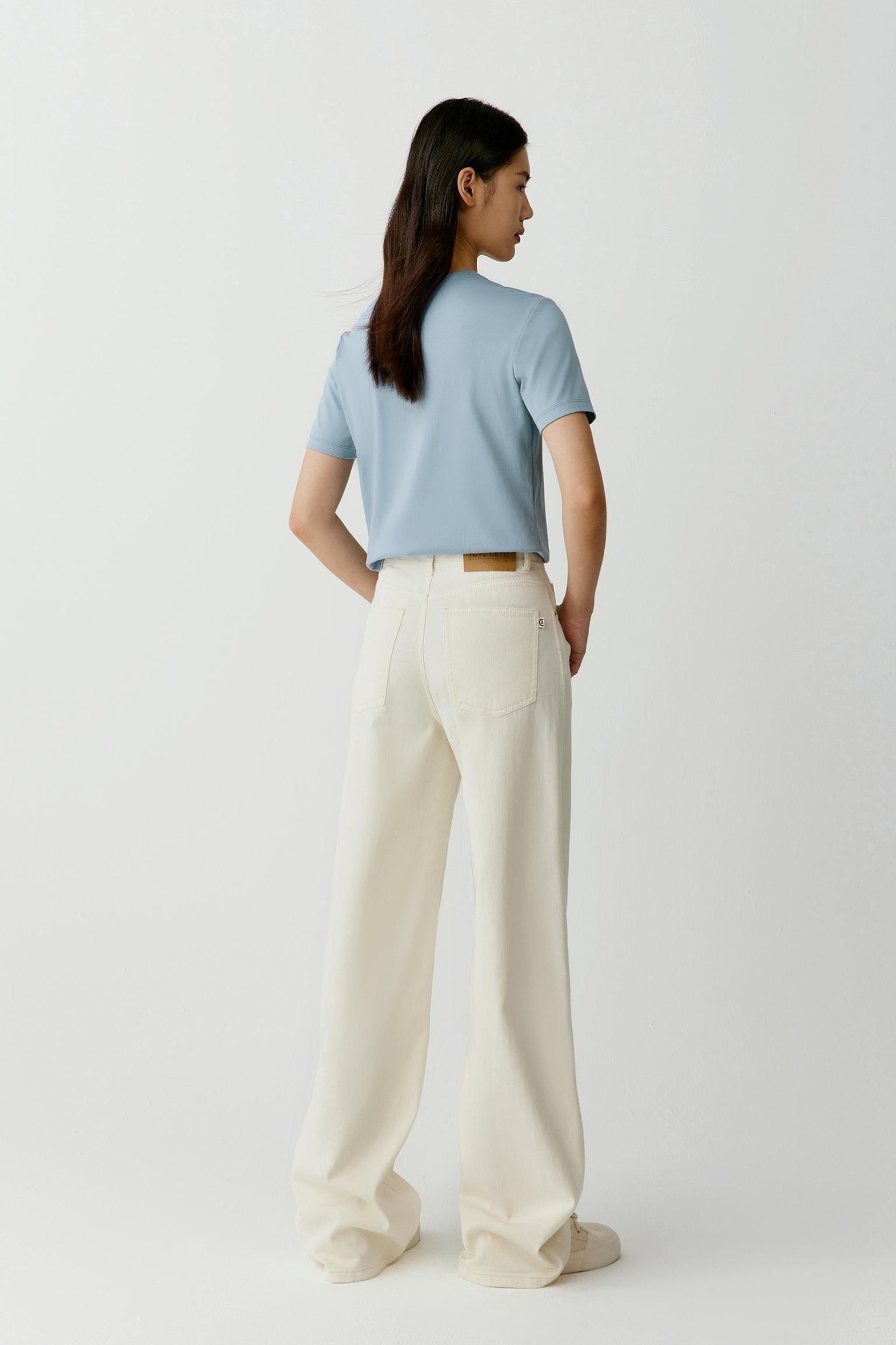 Back view illustrating the fluid drape and relaxed fit of the garment. The smooth jersey fabric maintains a soft structure without stiffness, creating a clean profile and natural movement through the body and sleeves.