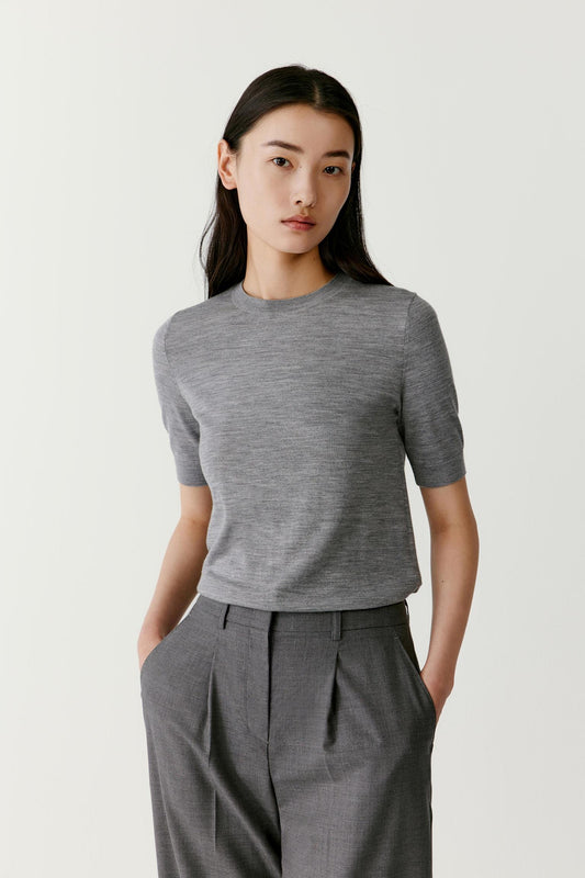Three-quarter view showing the balanced proportions of the tee and the fluid drape of the superfine wool knit. The round neckline sits close to the neck while the short sleeves create a clean minimal structure.