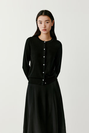 Full-length view of a woman wearing a deep black wool cardigan, highlighting the straight cut and long sleeves.