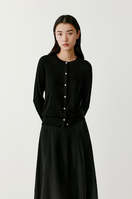 Full-length view of a woman wearing a deep black wool cardigan, highlighting the straight cut and long sleeves.