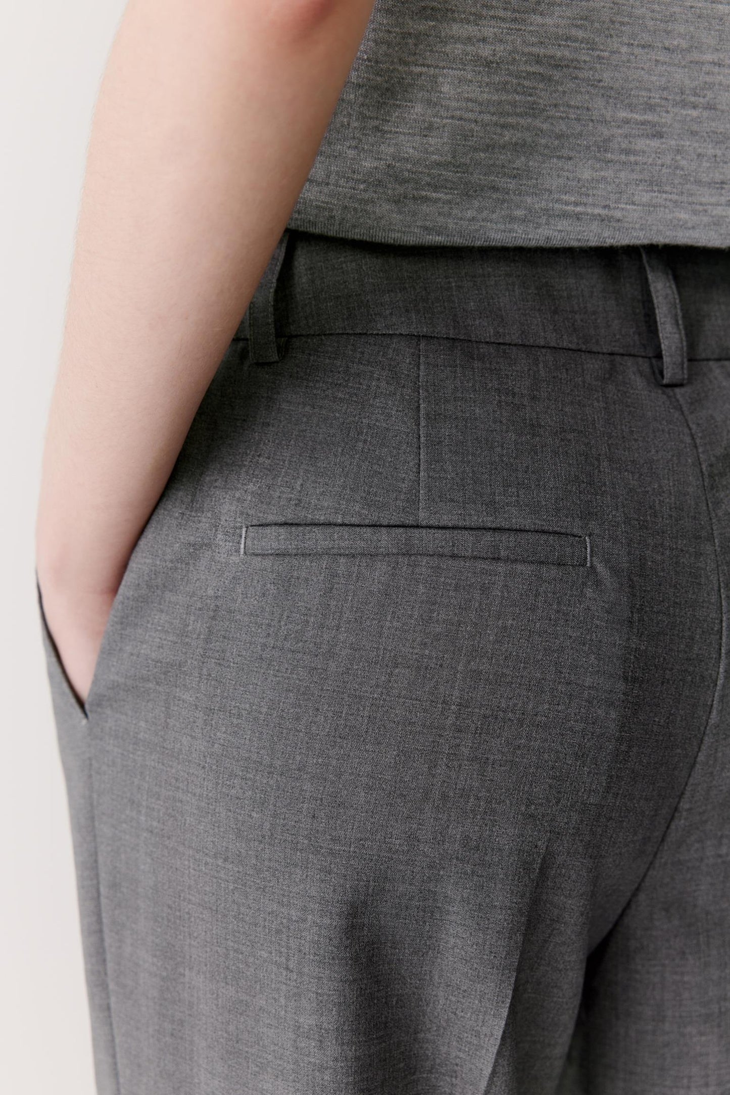 Close-up view of the side pocket area, showing the refined finish of the pocket opening, the clean side seam and the fluid drape of the worsted wool fabric. The image emphasizes the understated tailoring and soft structure of the garment.