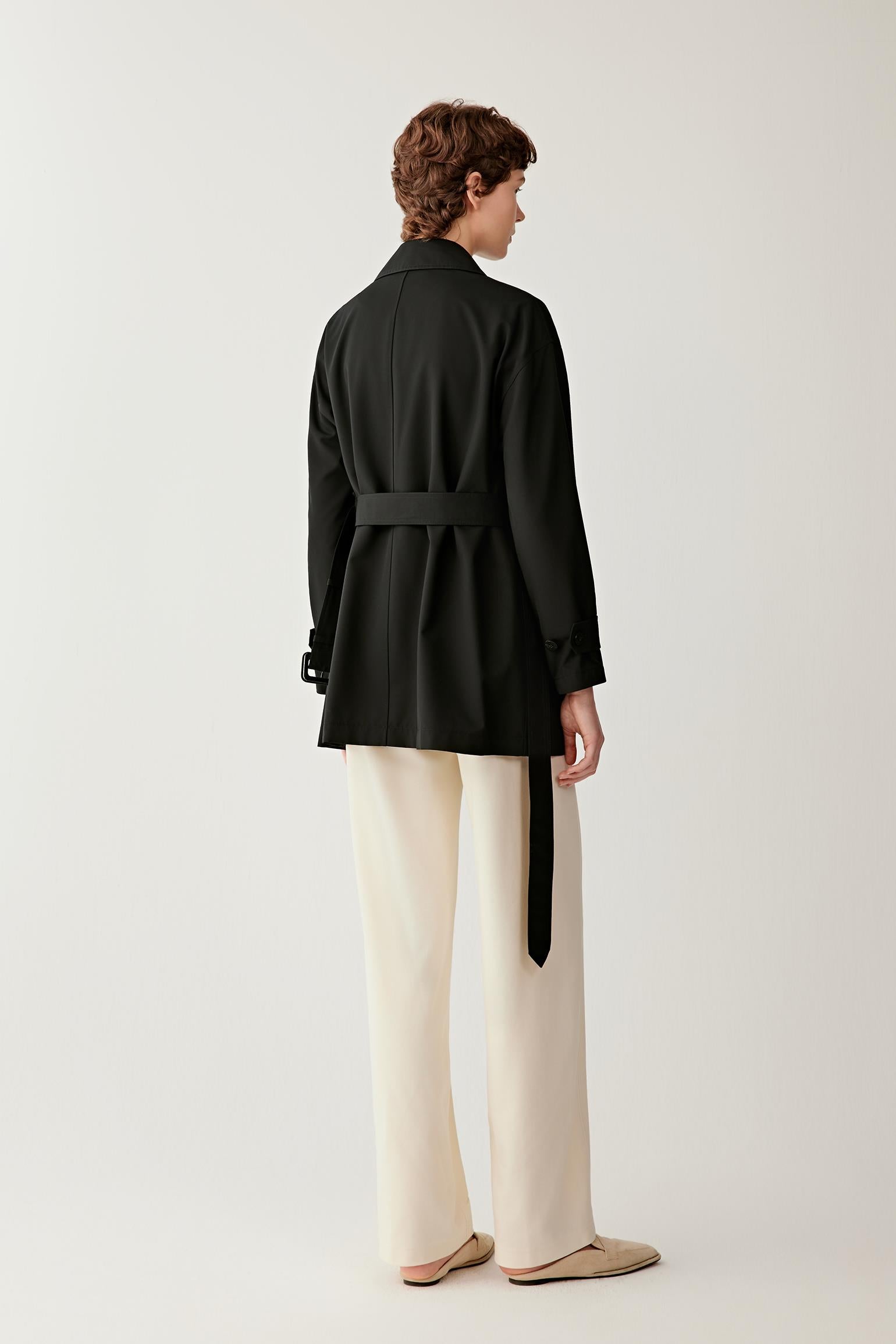 Back view highlighting the straight silhouette and clean construction of the garment. The image showcases the balanced proportions, long sleeves and smooth drape of the wool and silk fabric, creating a refined and understated appearance.