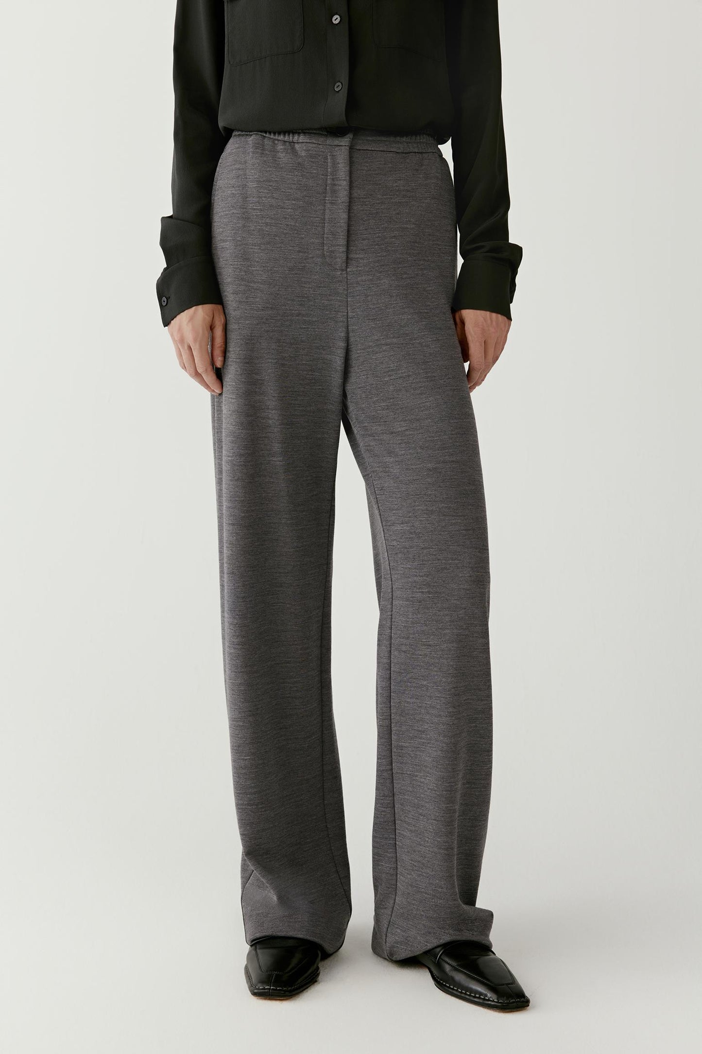 Person wearing gray wide-leg pants with a black top on a white background