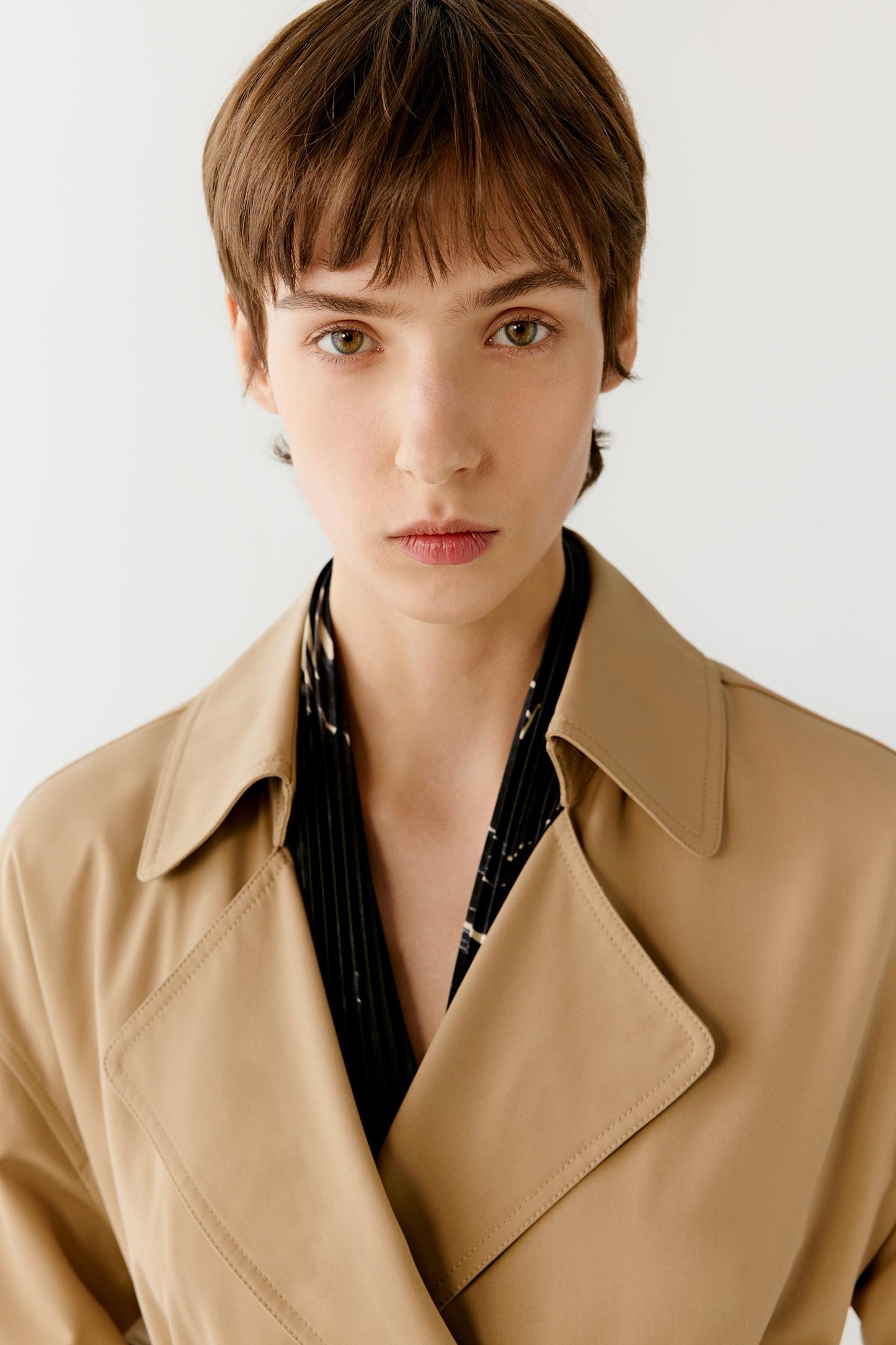 Close-up portrait focusing on the notched lapels, collar construction and upper section of the coat. The image reveals the smooth surface of the wool and silk fabric, the precise tailoring and the clean finishing that shape the neckline and front opening.
